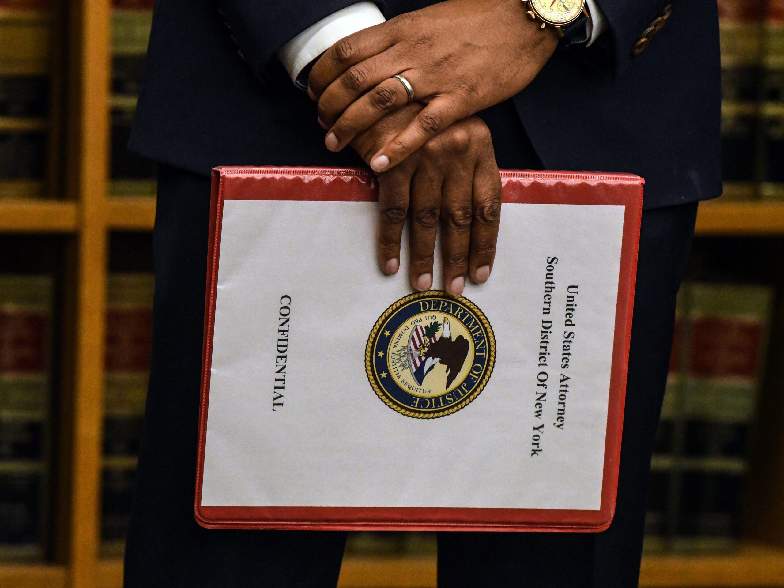 Hands holding a file with cover titled &#34;United States Attorney Southern District of New York.&#34;