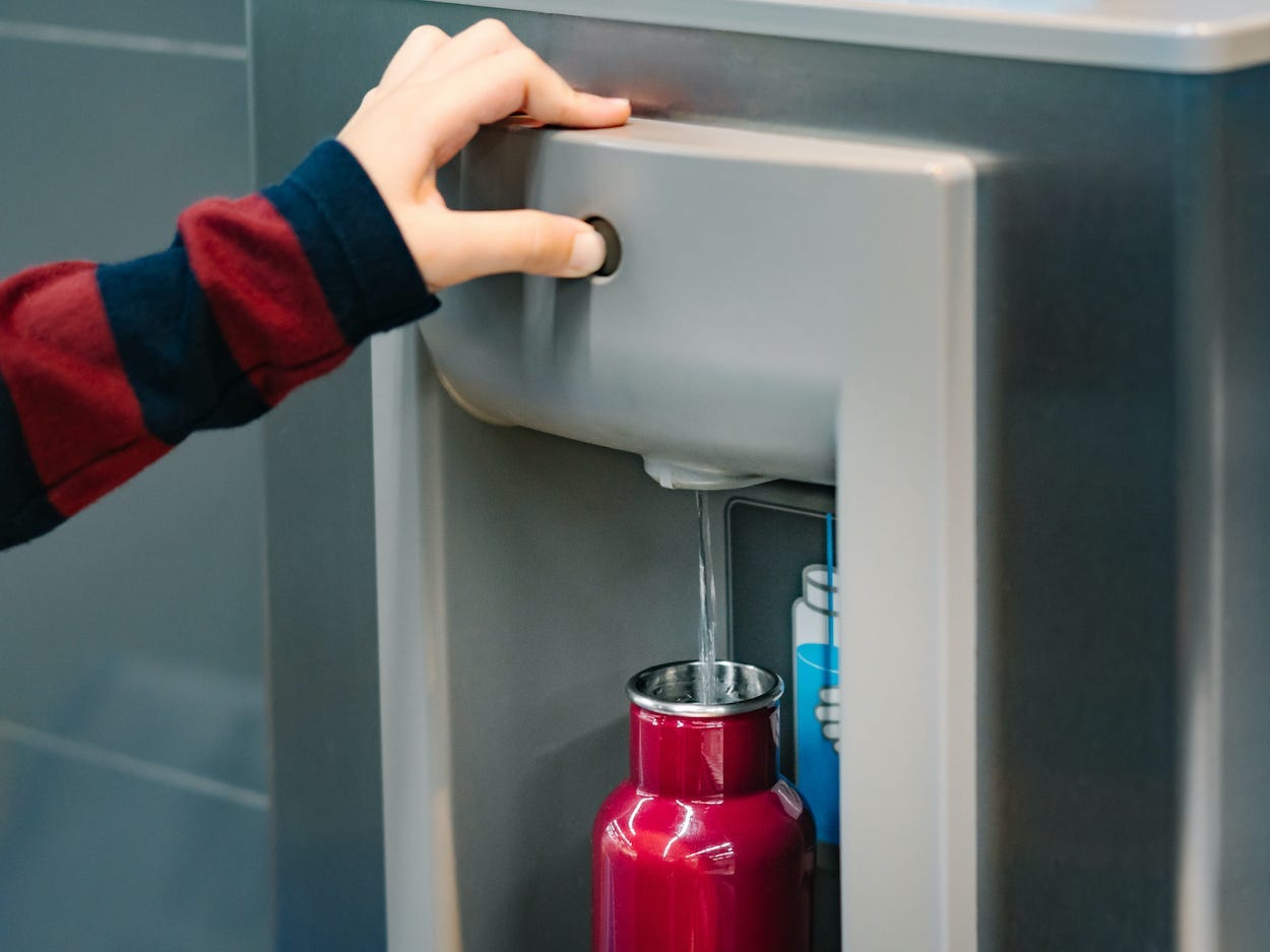 A person fills up their reusable water bottle at an airport.