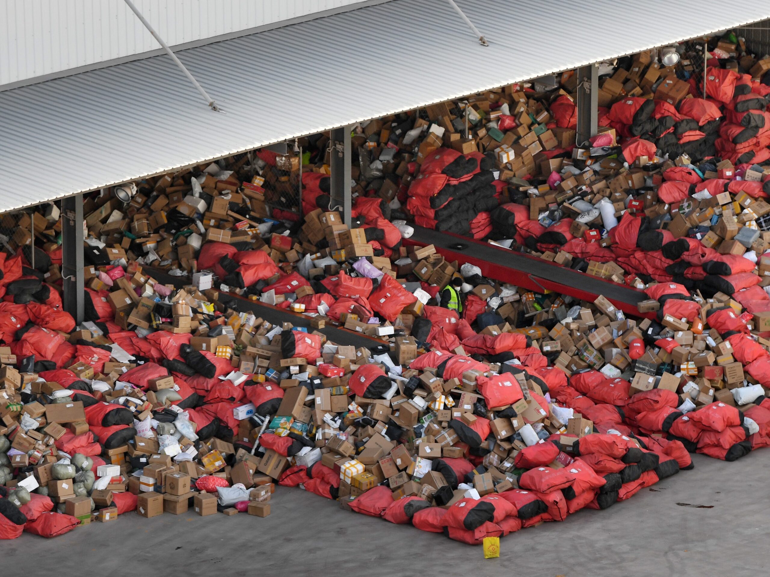 Thousands of packages, some in red sacks, are piled up in a Chinese warehouse ready to be delivered.