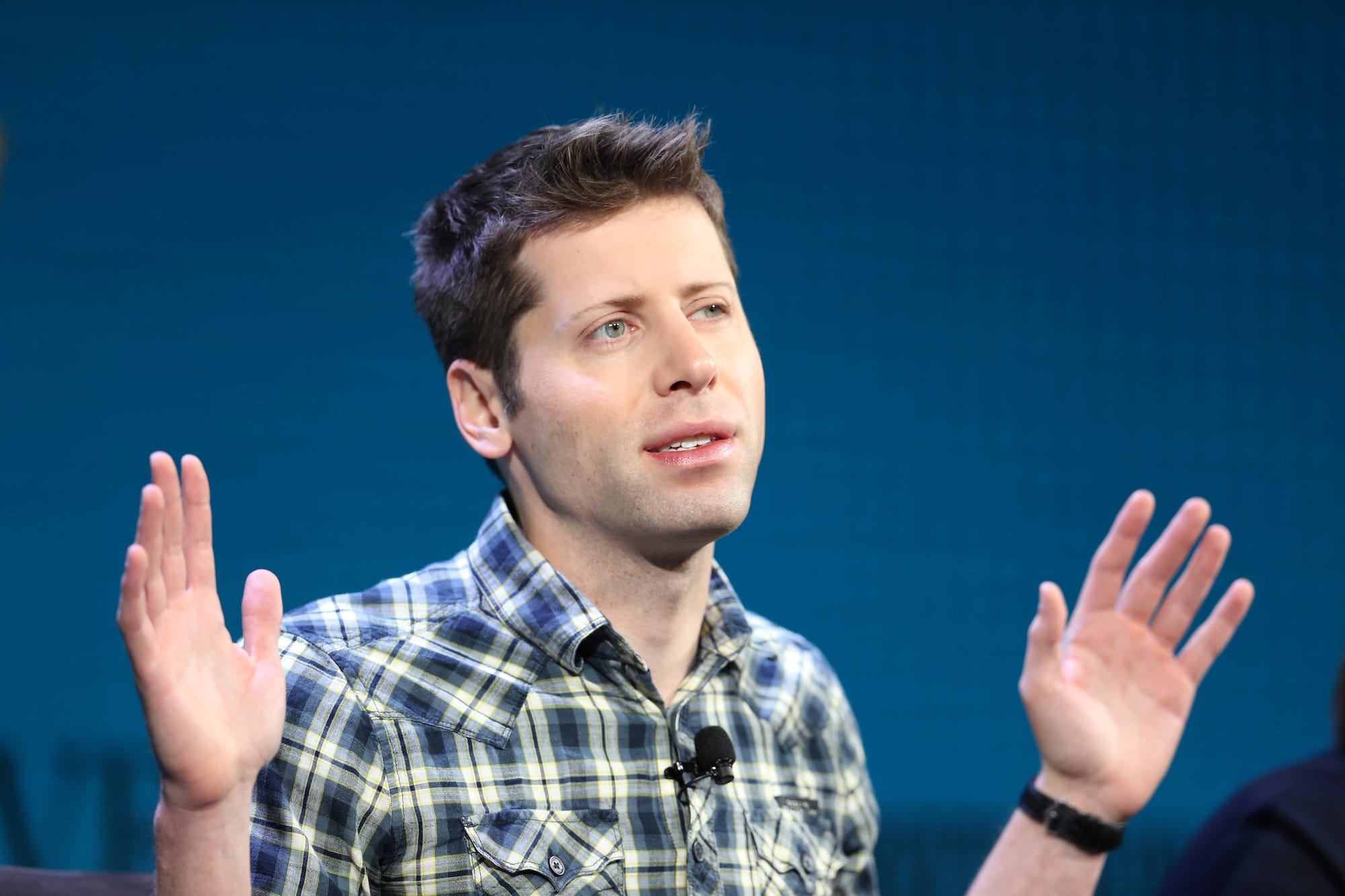 An image of Sam Altman, the CEO of OpenAI, speaking on a stage.