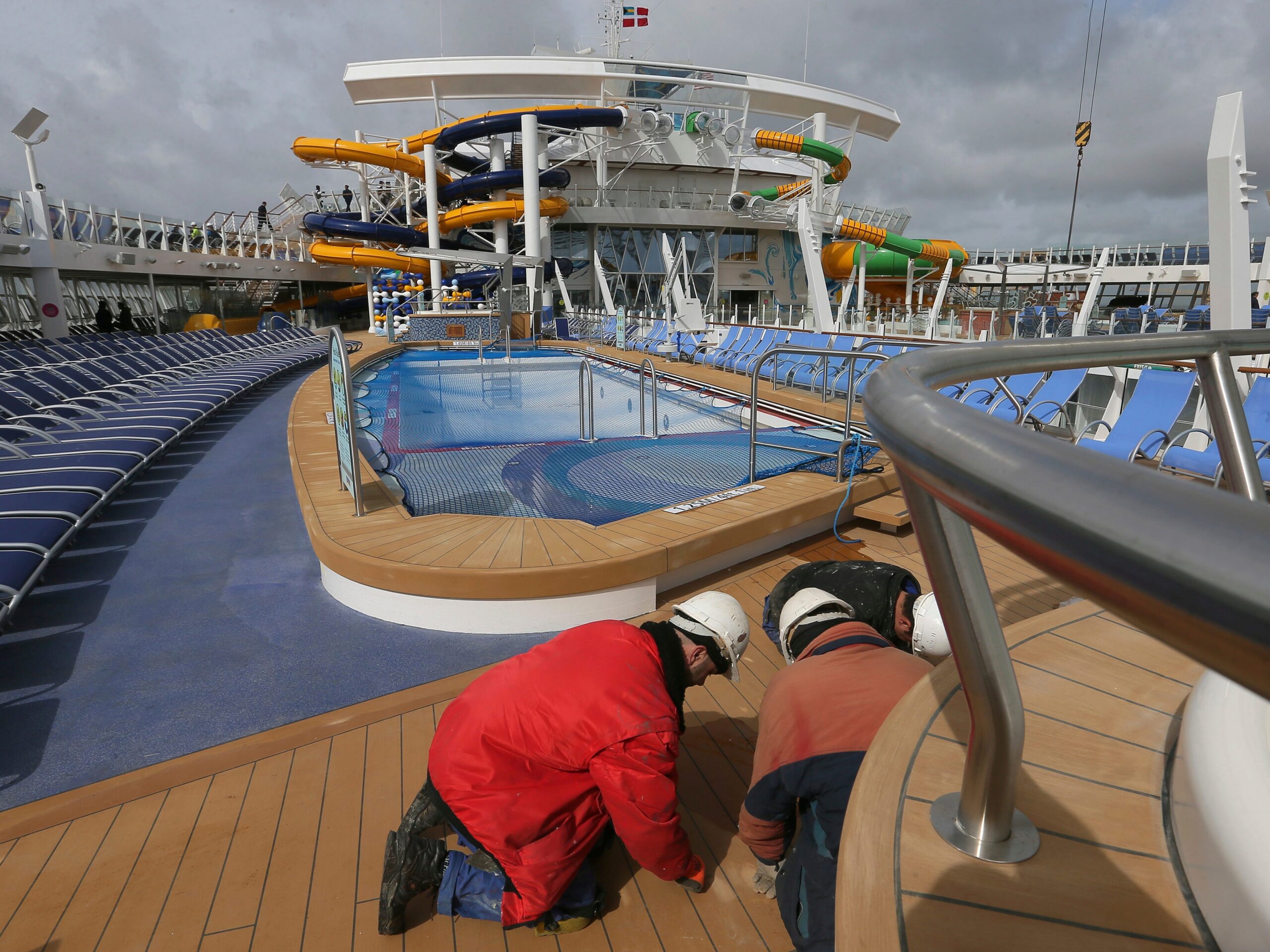 Workers near the swimming pool aboard The Symphony of the Seas, the world's largest cruise ship, docking at Saint Nazaire port, western France, Friday, March 23, 2018.