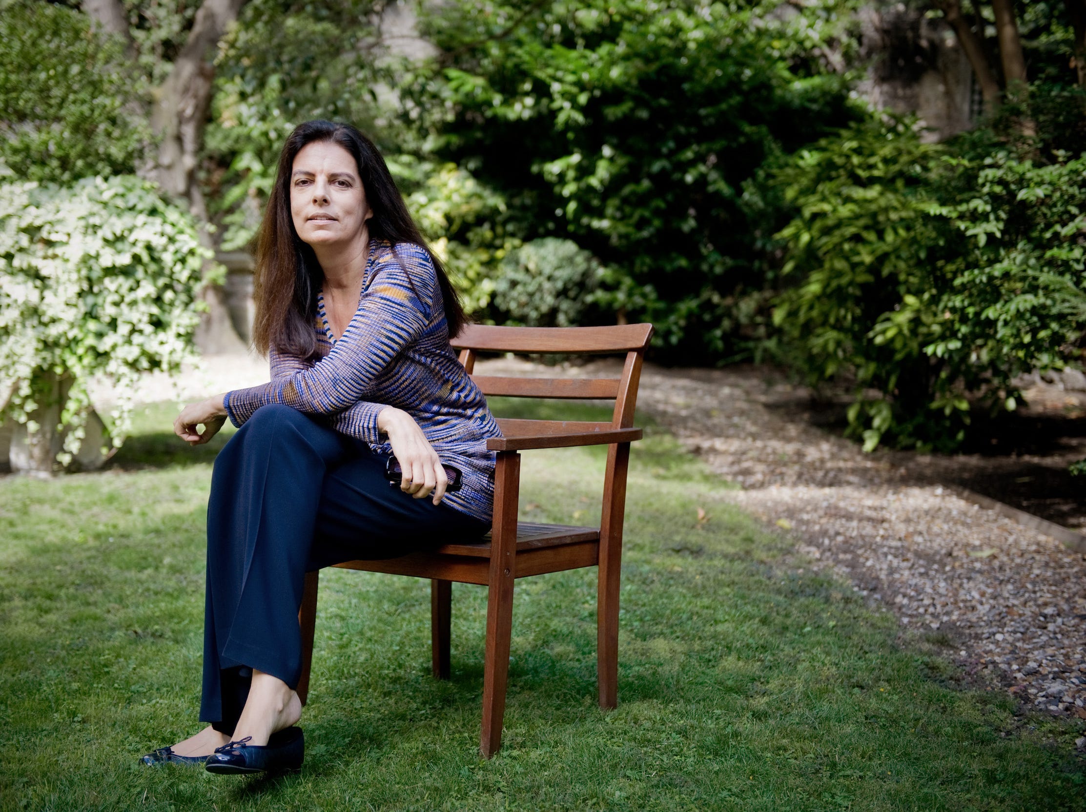 Francoise Bettencourt Meyers sits on a chair in an outdoor garden