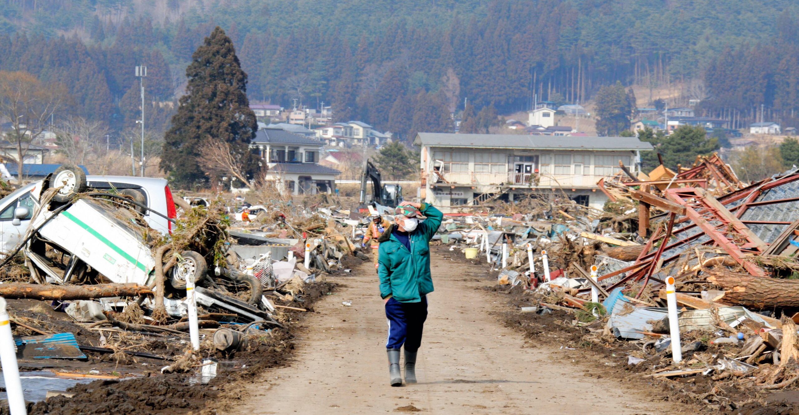 Man met beschermend masker loopt door het volledig door de tsunami van 11 maart 2011 grotendeels verwoeste Japanse dorpje Noda. Foto: EPA/Asahi Shimbun.