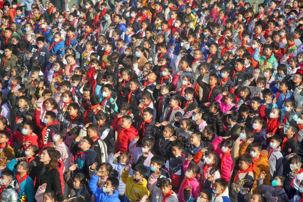 Basisschoolleerlingen brengen een groet tijdens het hijsen van de nationale vlag in Yantai, de Oost-Chinese provincie Shandong.