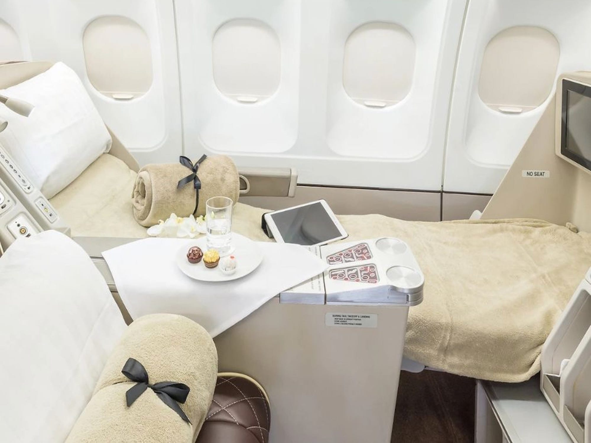 AirX Charters' A340 business class seat in lie-flat mode with beige linens.