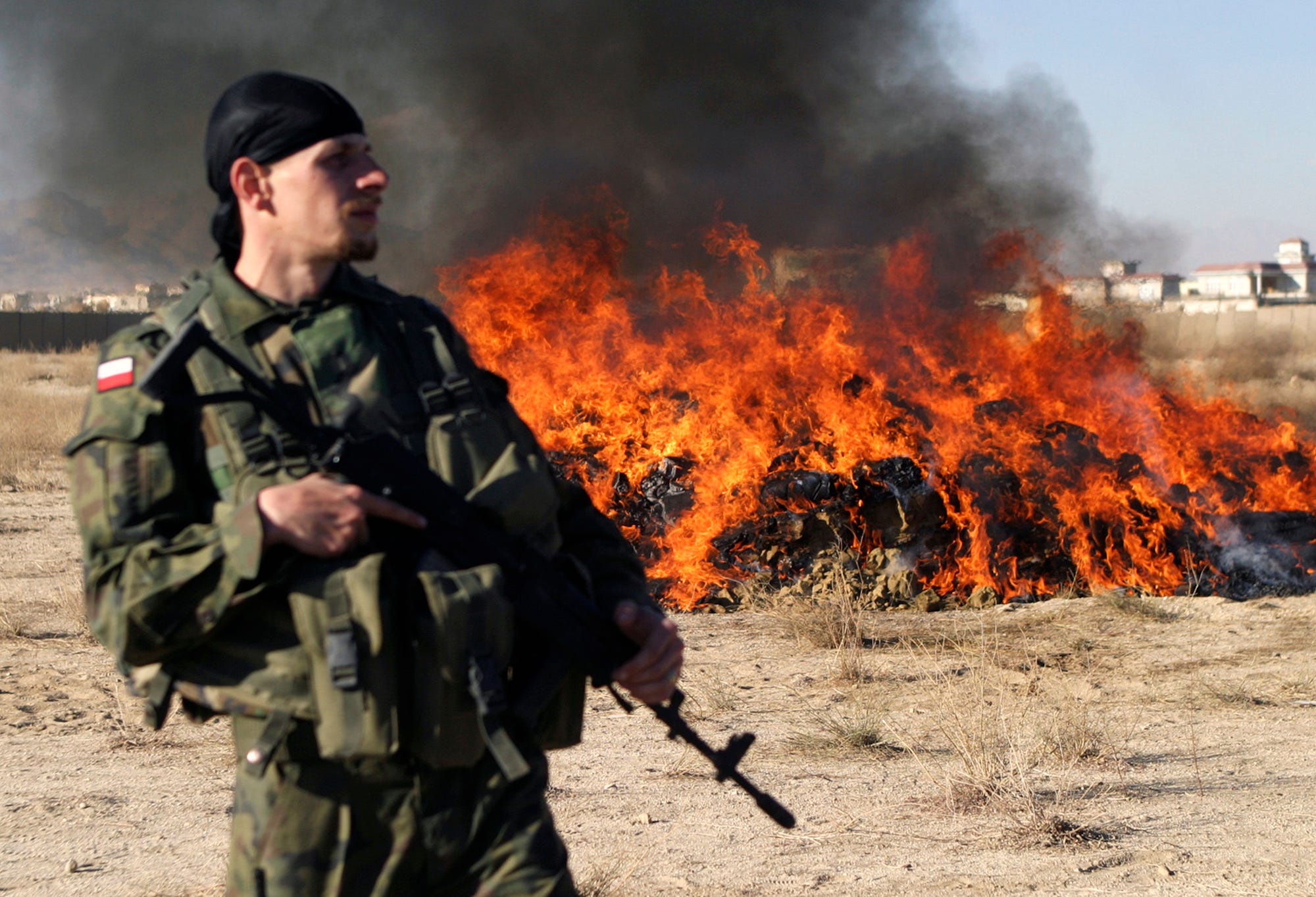 A Polish soldier stands guard in front of a pile of burning illegal narcotics in Afghanistan&#39;s Ghazni province in November 2008