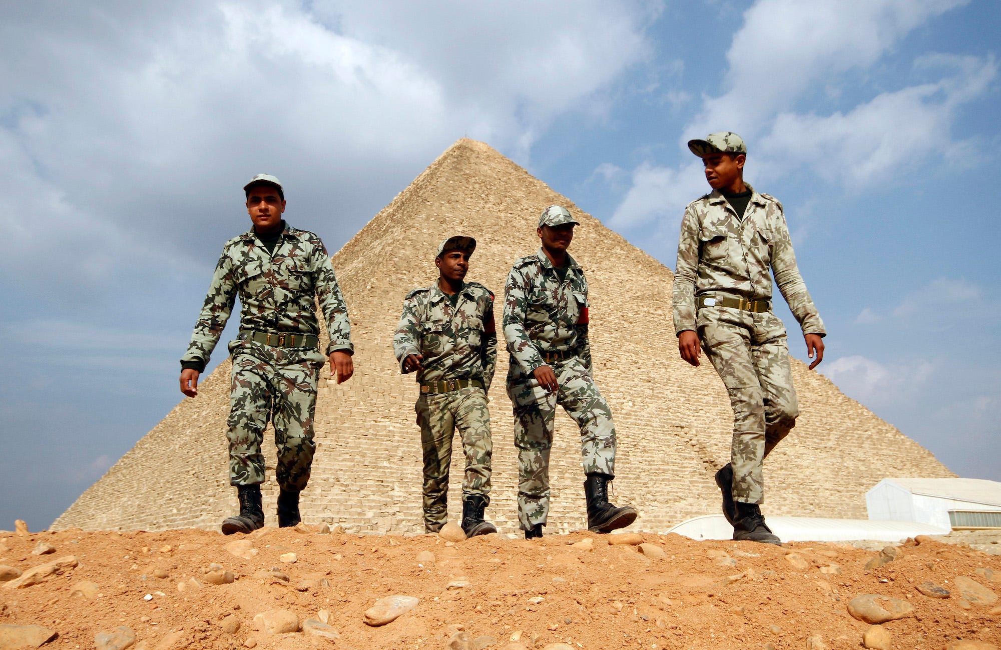 Egyptian soldiers walk in front of the Great Giza pyramids on the outskirts of Cairo February 9, 2011.