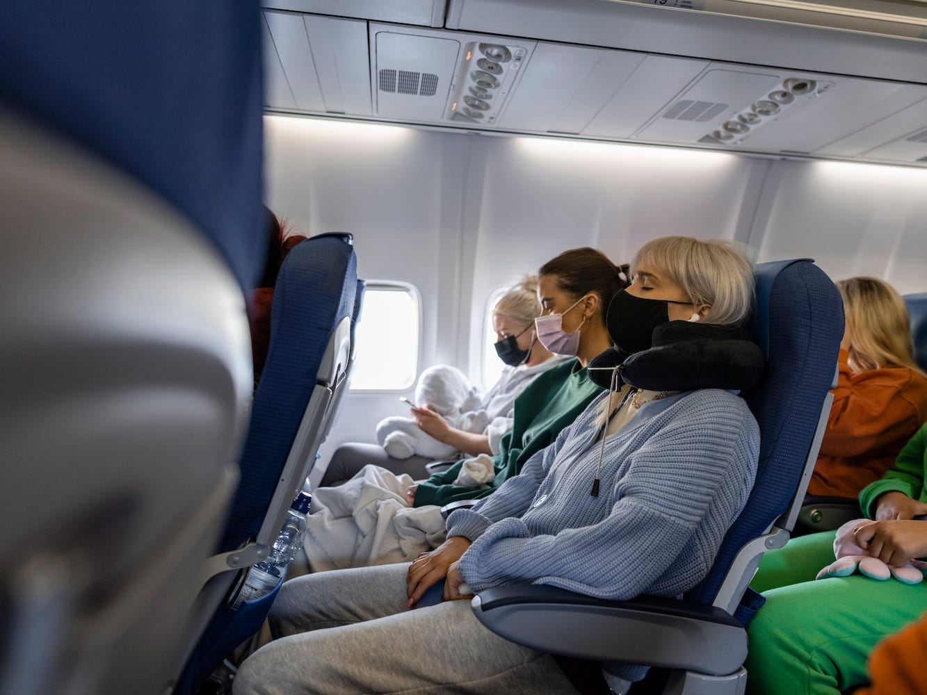 Travelers wear face masks on an airplane.