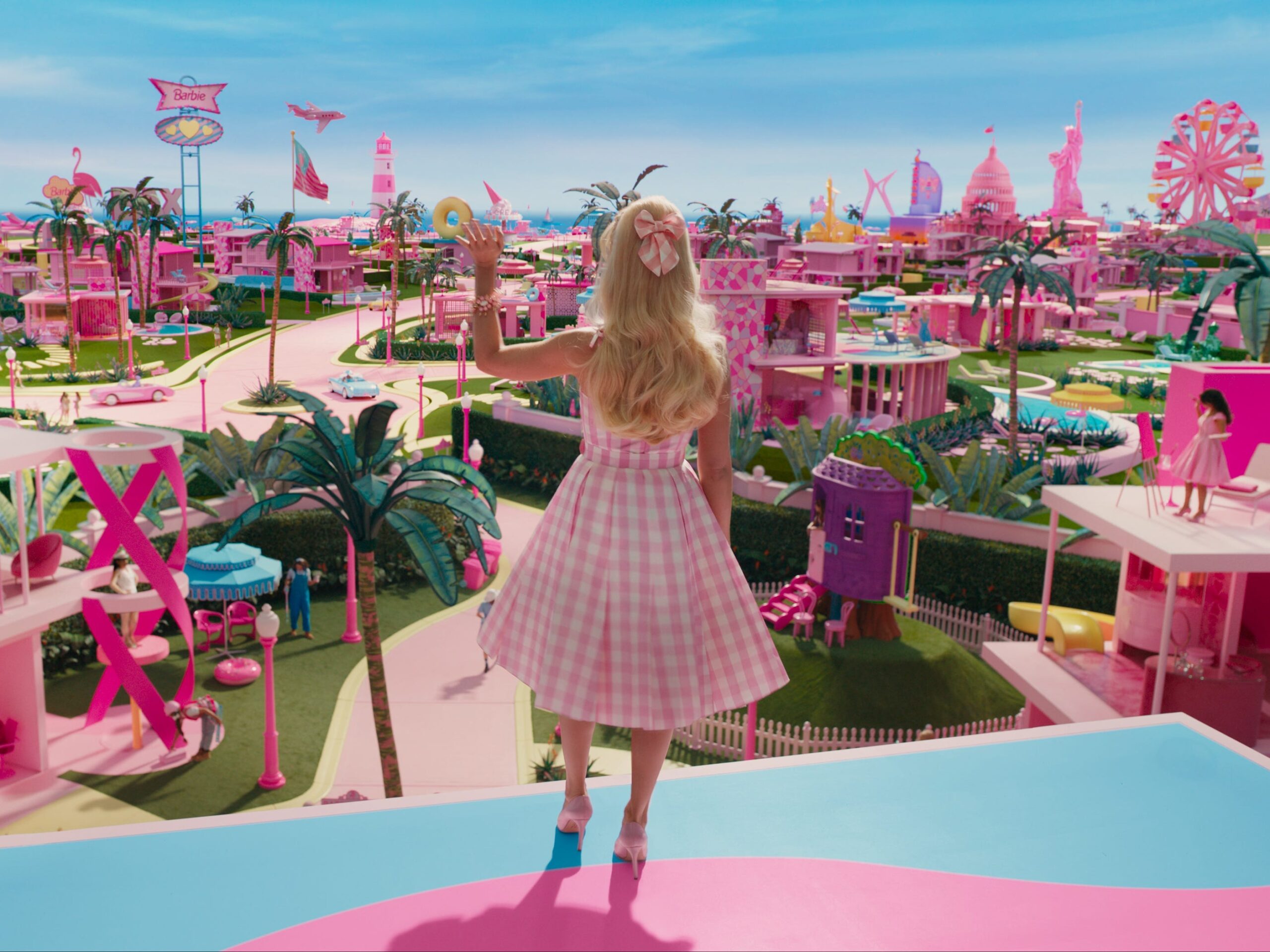 Margot Robbie&#39;s Barbie waving to Barbie Land citizens in &#34;Barbie.&#34;