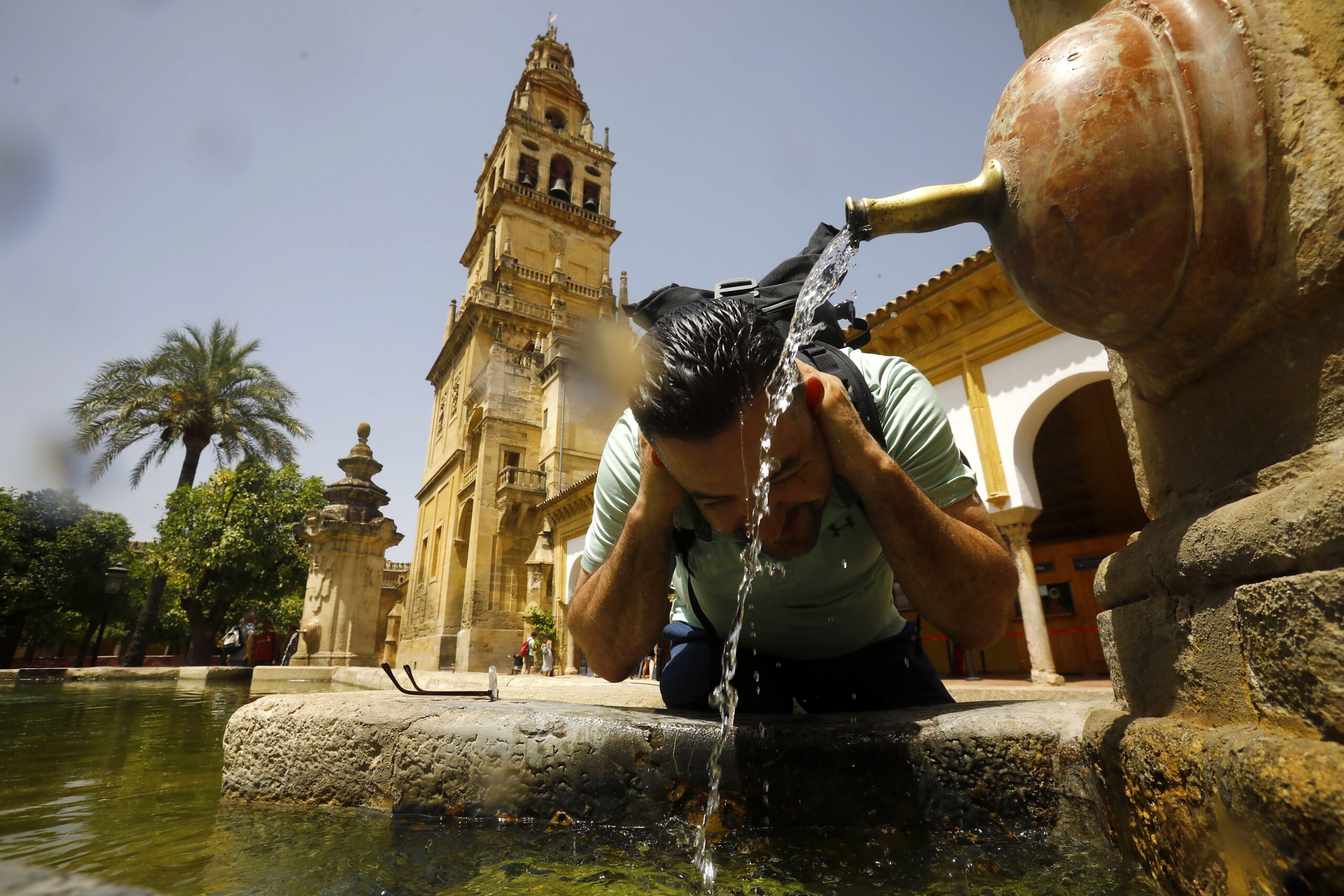 Een man zoekt verkoeling bij een watertappunt in het Spaanse Cordoba in juli 2022. Het is er 43 graden.