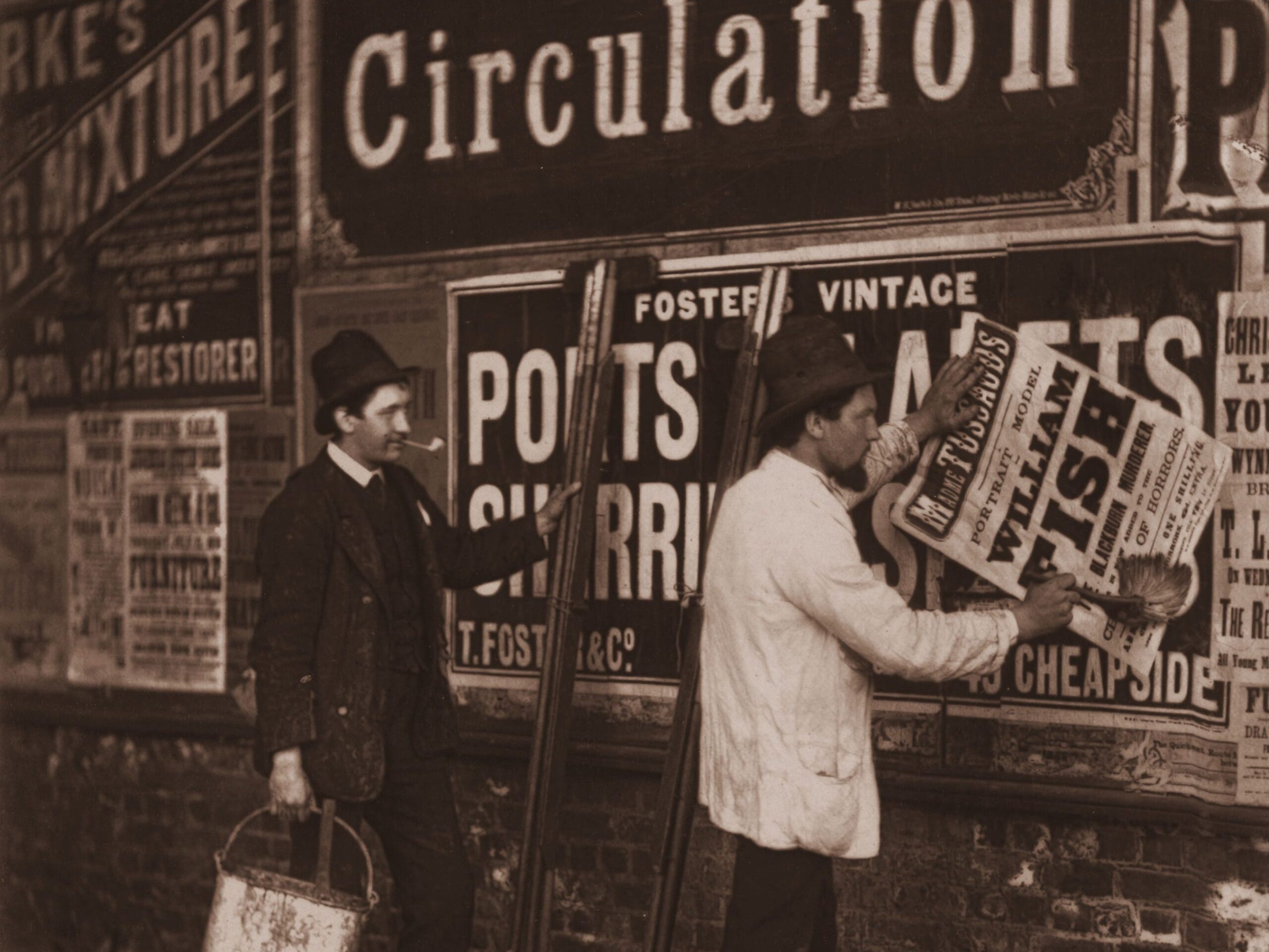 1877: Victorian bill stickers paste placards advertising Madame Tussaud&#39;s waxworks museum in London.