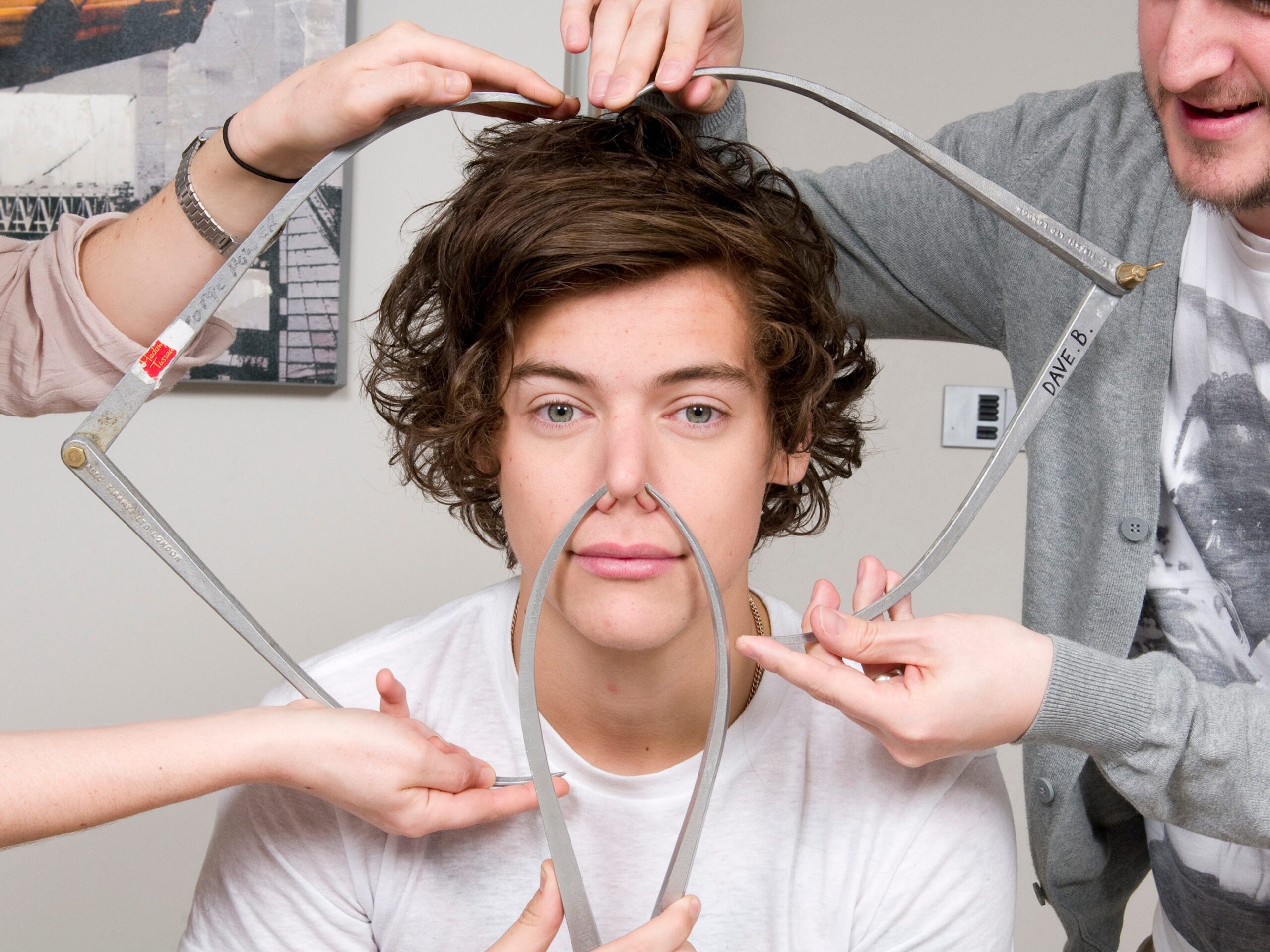 Harry Styles of One Direction poses with calipers during a figure sitting where he is measured for a wax figure creation in 2013.