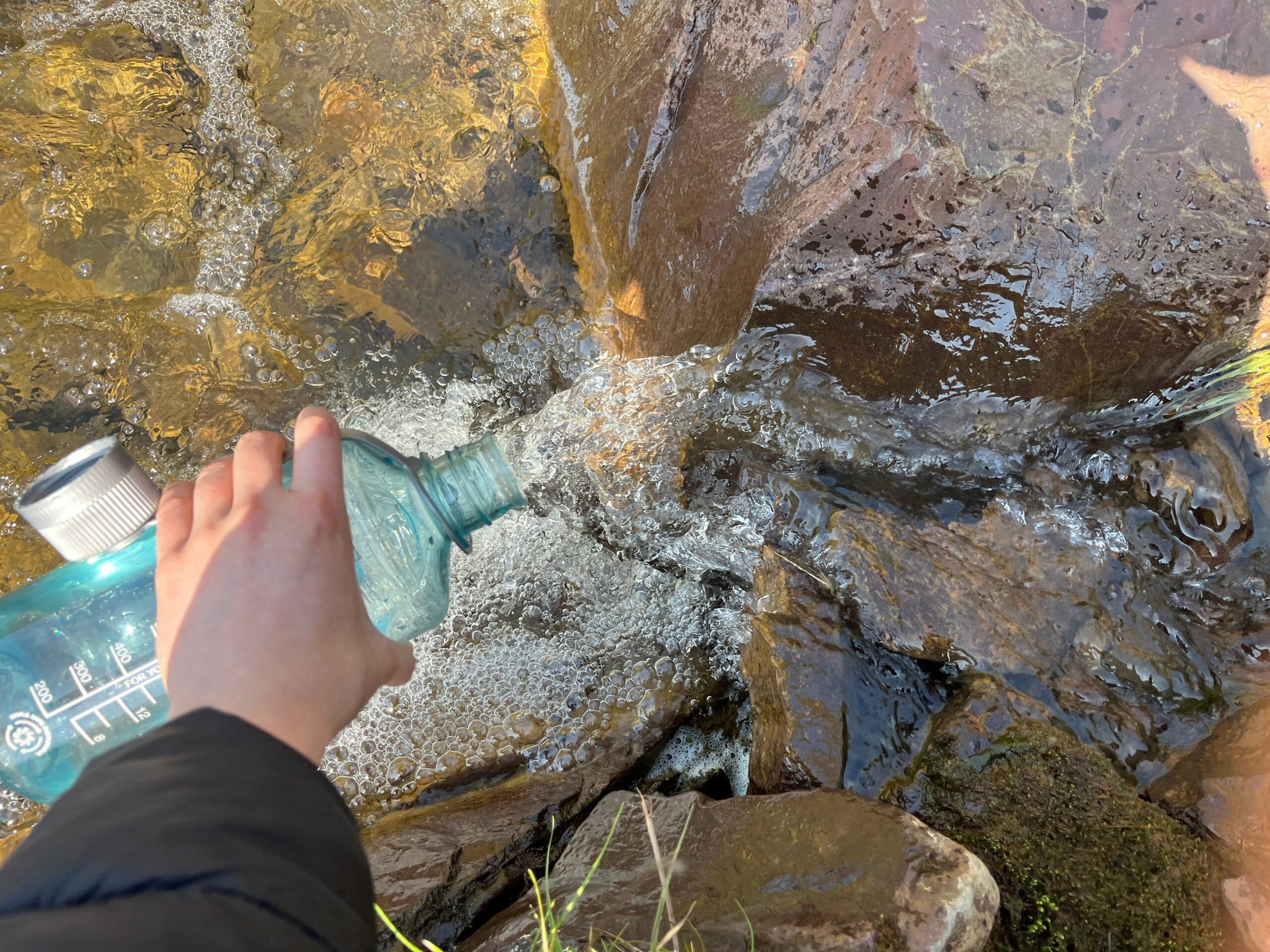 Filling a water bottle in a stream in Iceland
