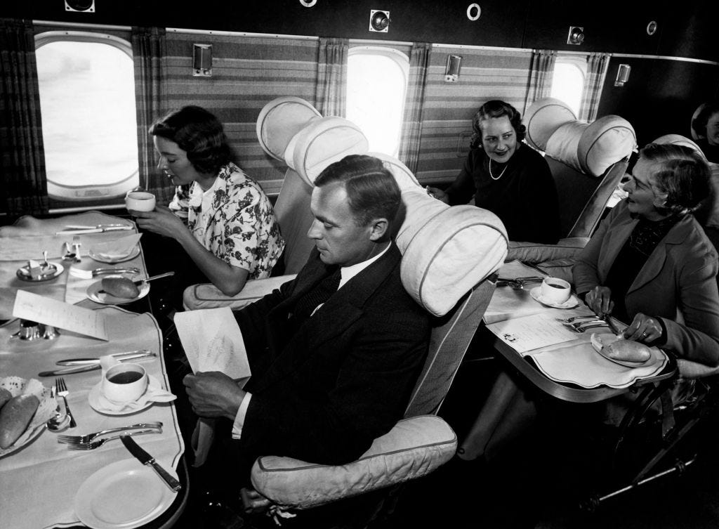 Passengers eat a meal on a plane in the 1950s.