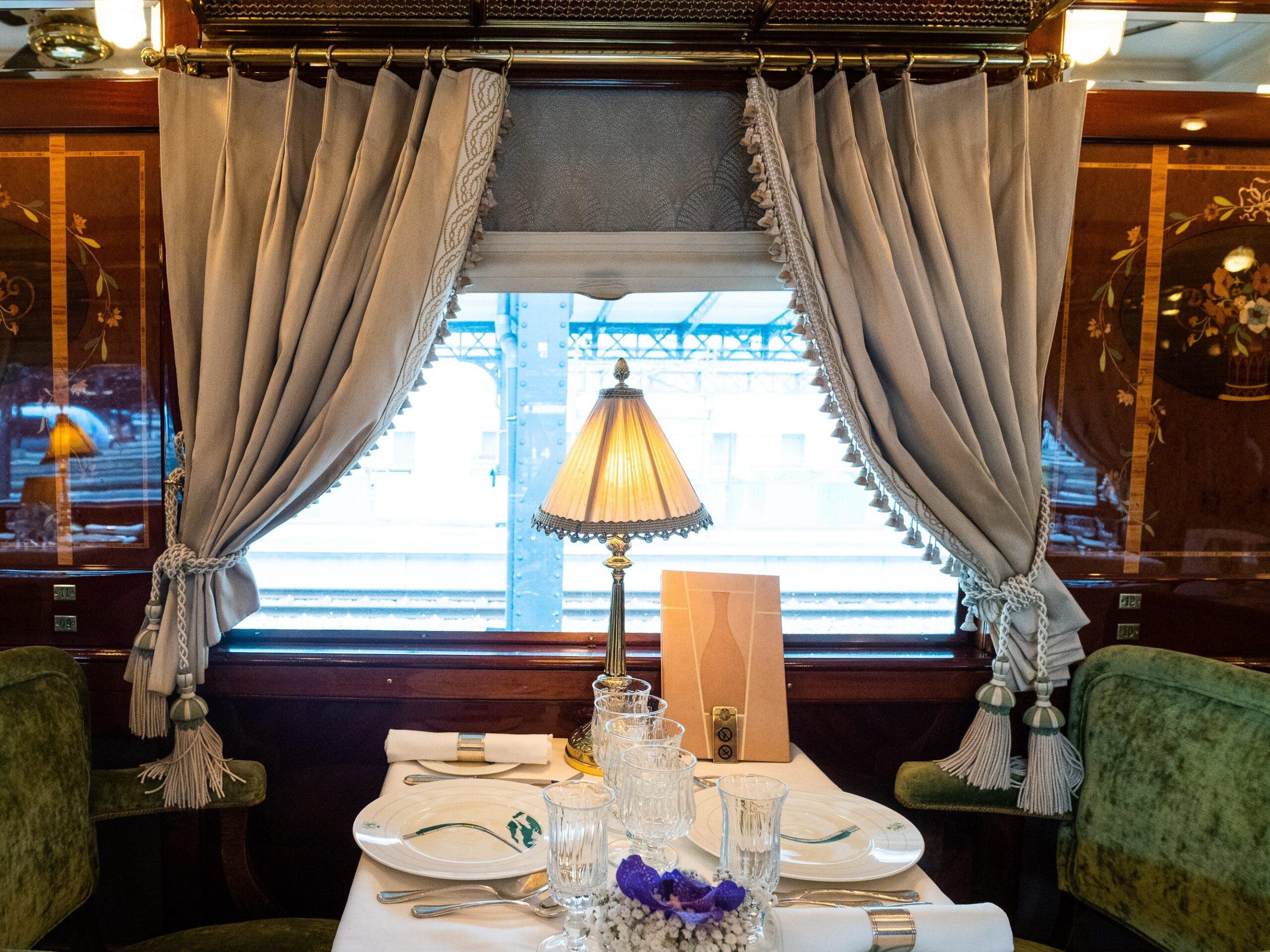 A dining table with a lamp on it on a luxury train