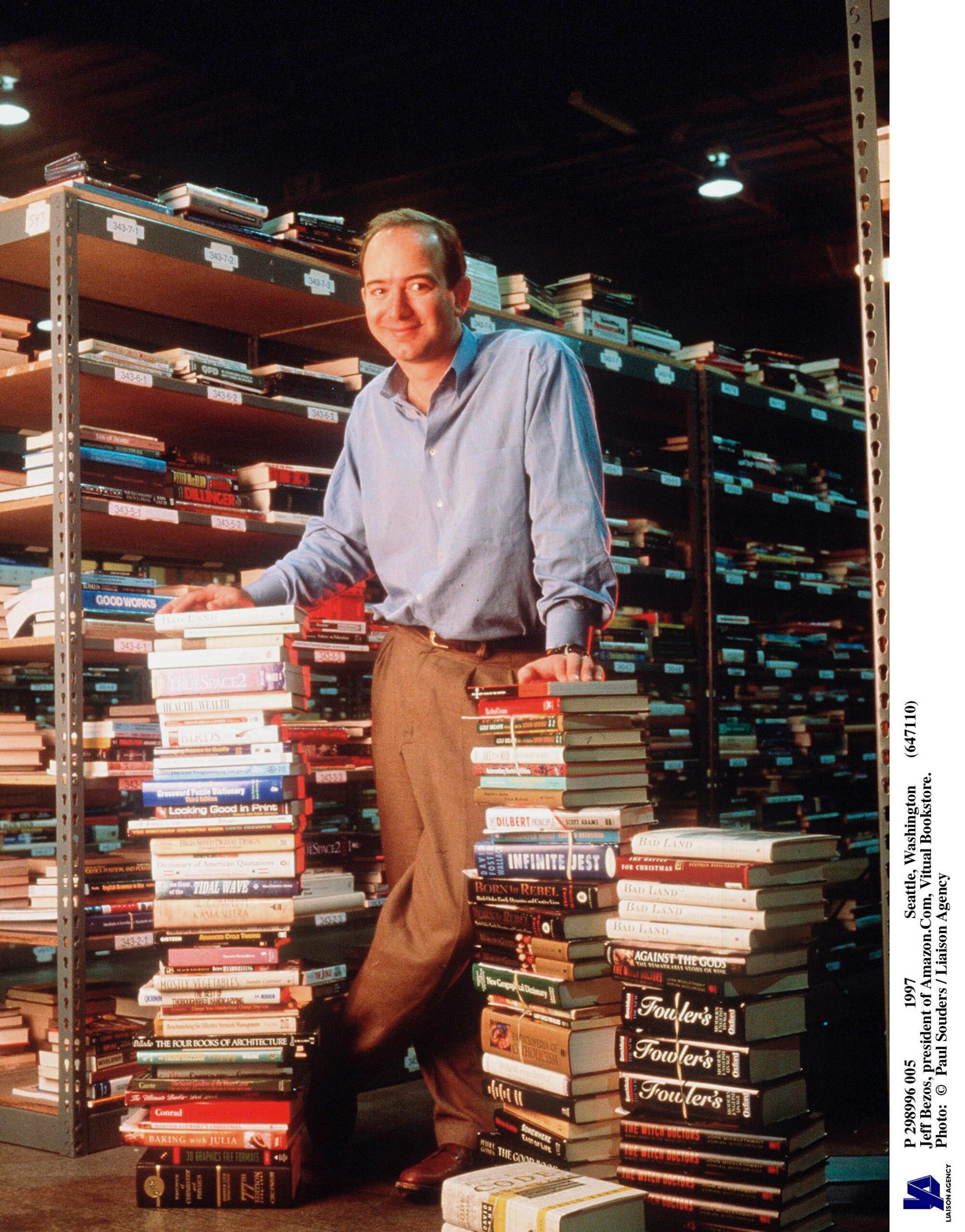 Jeff Bezos stood whilst leaning on two stacks of books