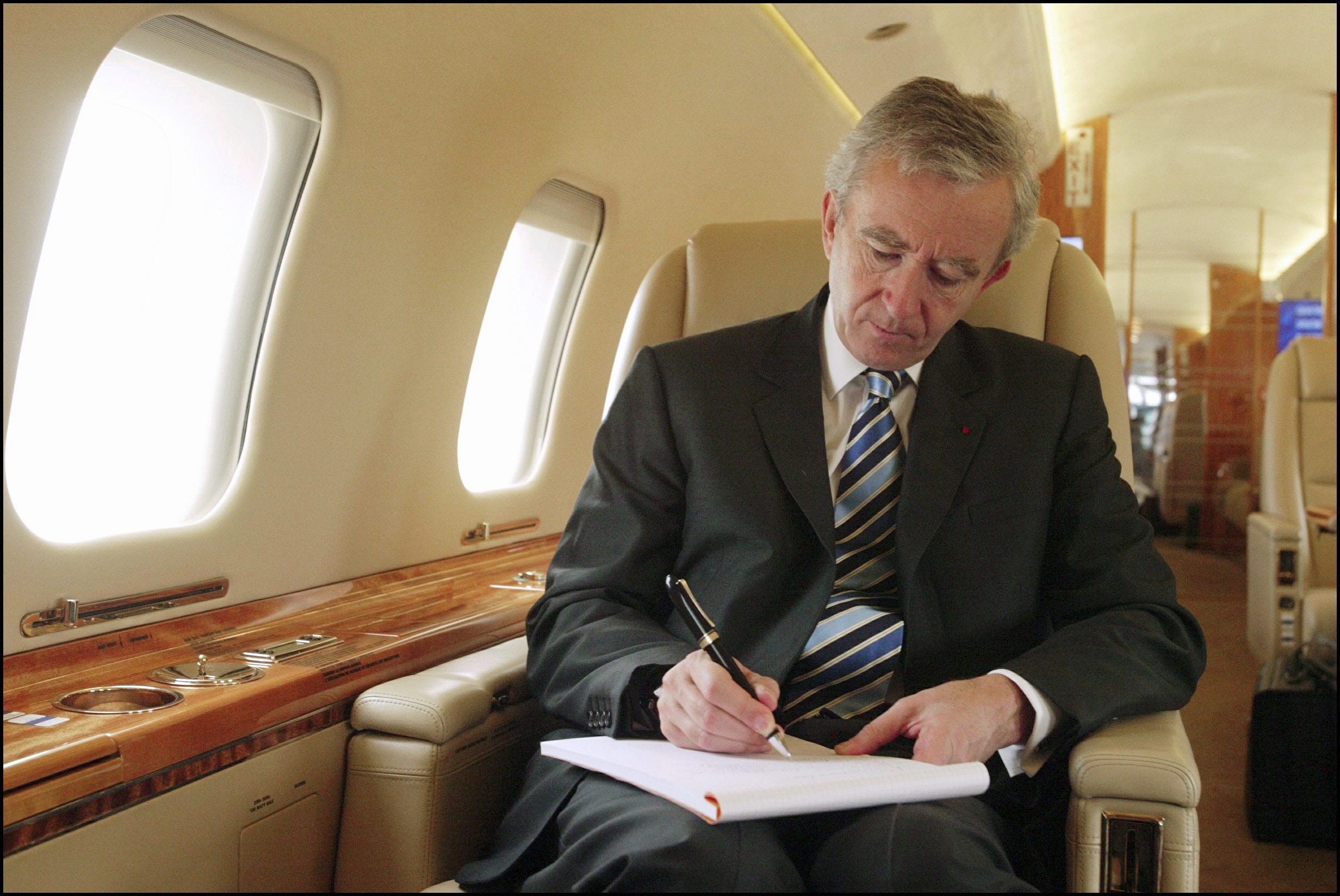 Bernard Arnault on a private jet signing a document