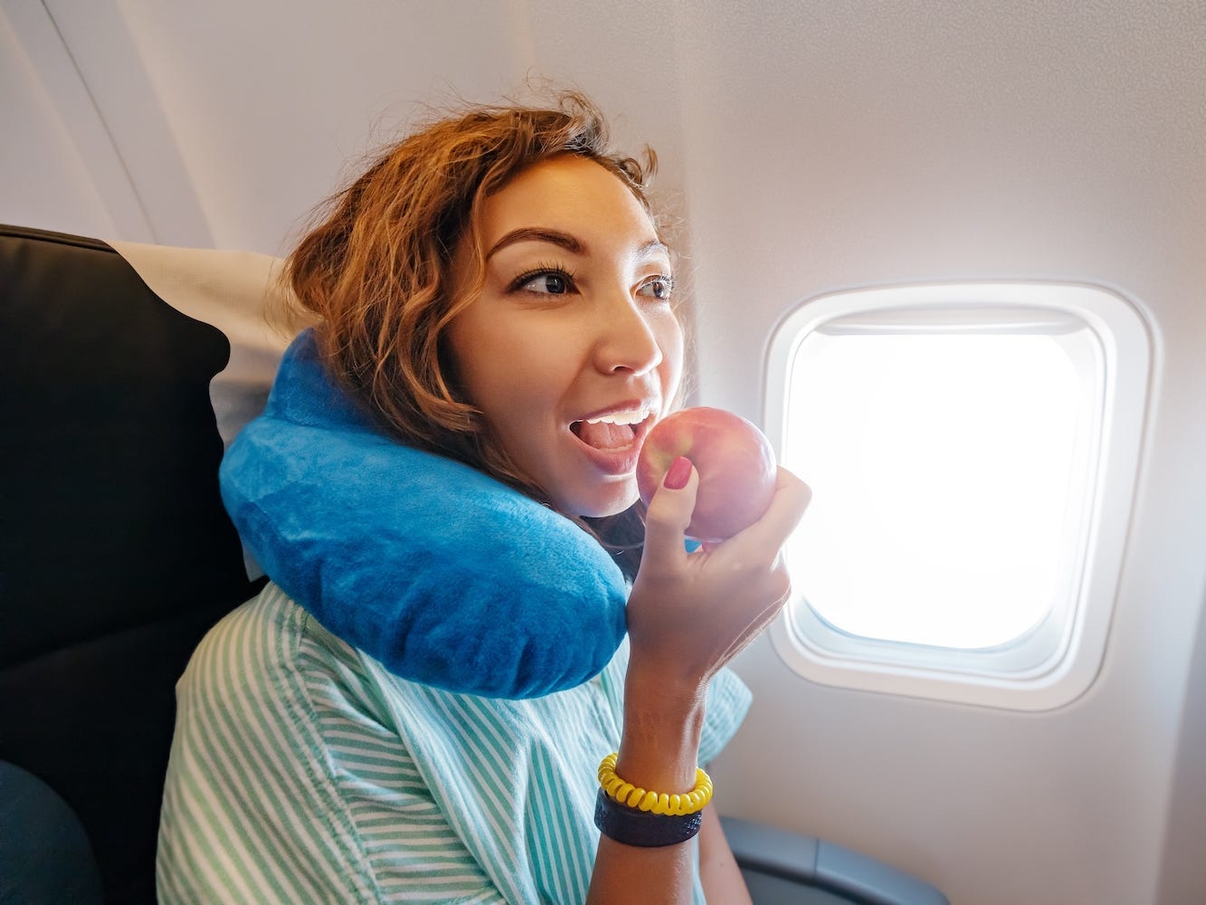 Een vrouw eet een appel in een vliegtuig.