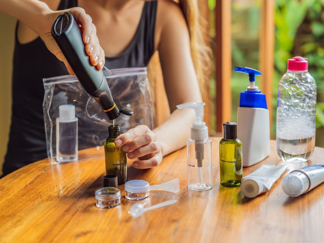 A person transfers toiletries into smaller containers.