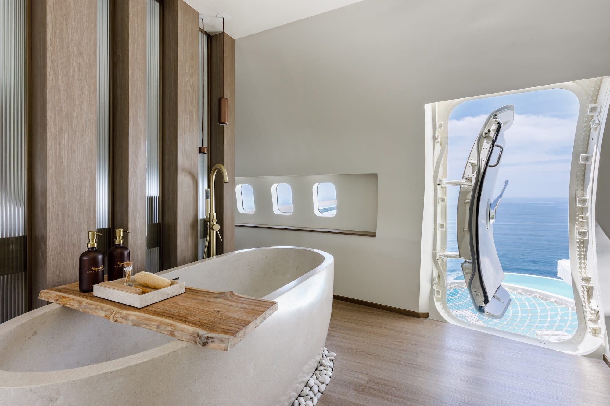 Een badkuip in het vliegtuig. De zijdeur van het vliegtuig staat open, met uitzicht op een zwembad.