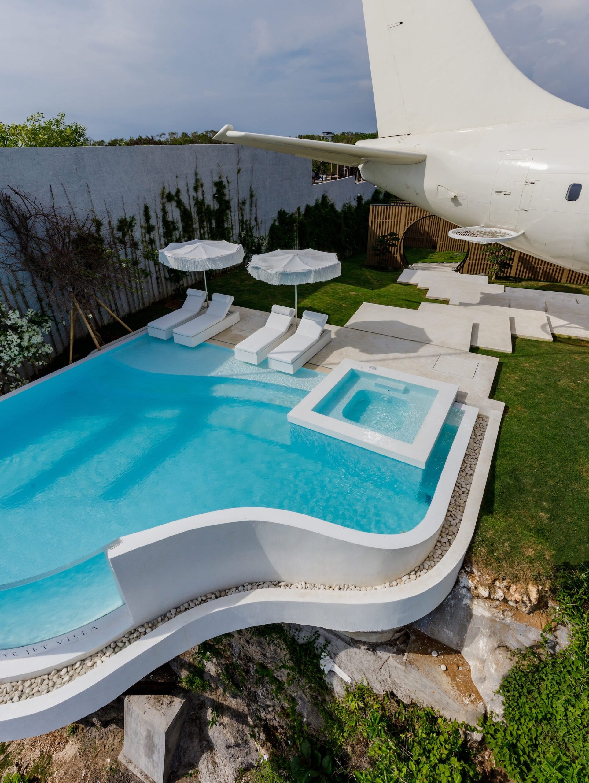 Naast het tot villa omgebouwde vliegtuig ligt een zwembad. Dat kijkt uit over het strand.