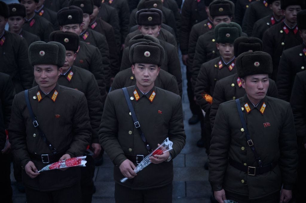 Korean People's Army (KPA) soldiers hold flowers as they pay their respects before a statue of late North Korean leader Kim Jong Il.