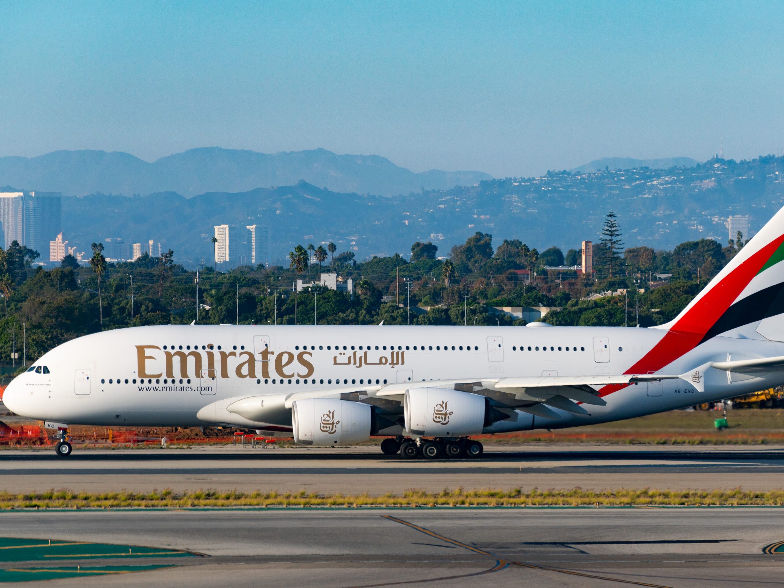 Emirates Airlines Airbus A380-842 prepares for takeoff at Los Angeles International Airport with the city and mountains in the background