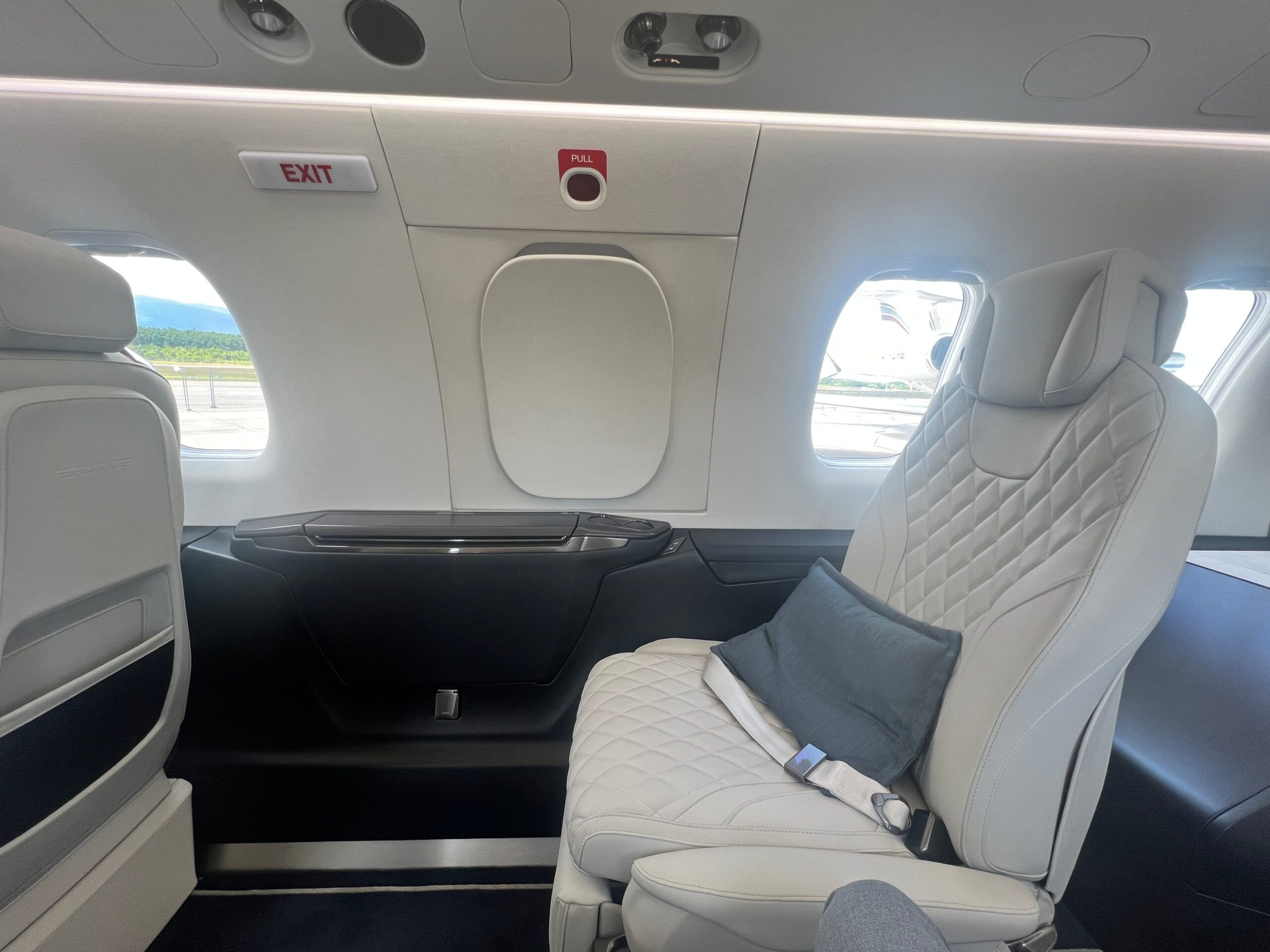 A close up of a seat and the overwing emergency exit on board a Pilatus PC-24