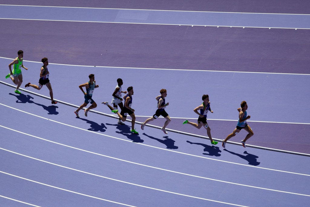 Athletes run on a purple track.