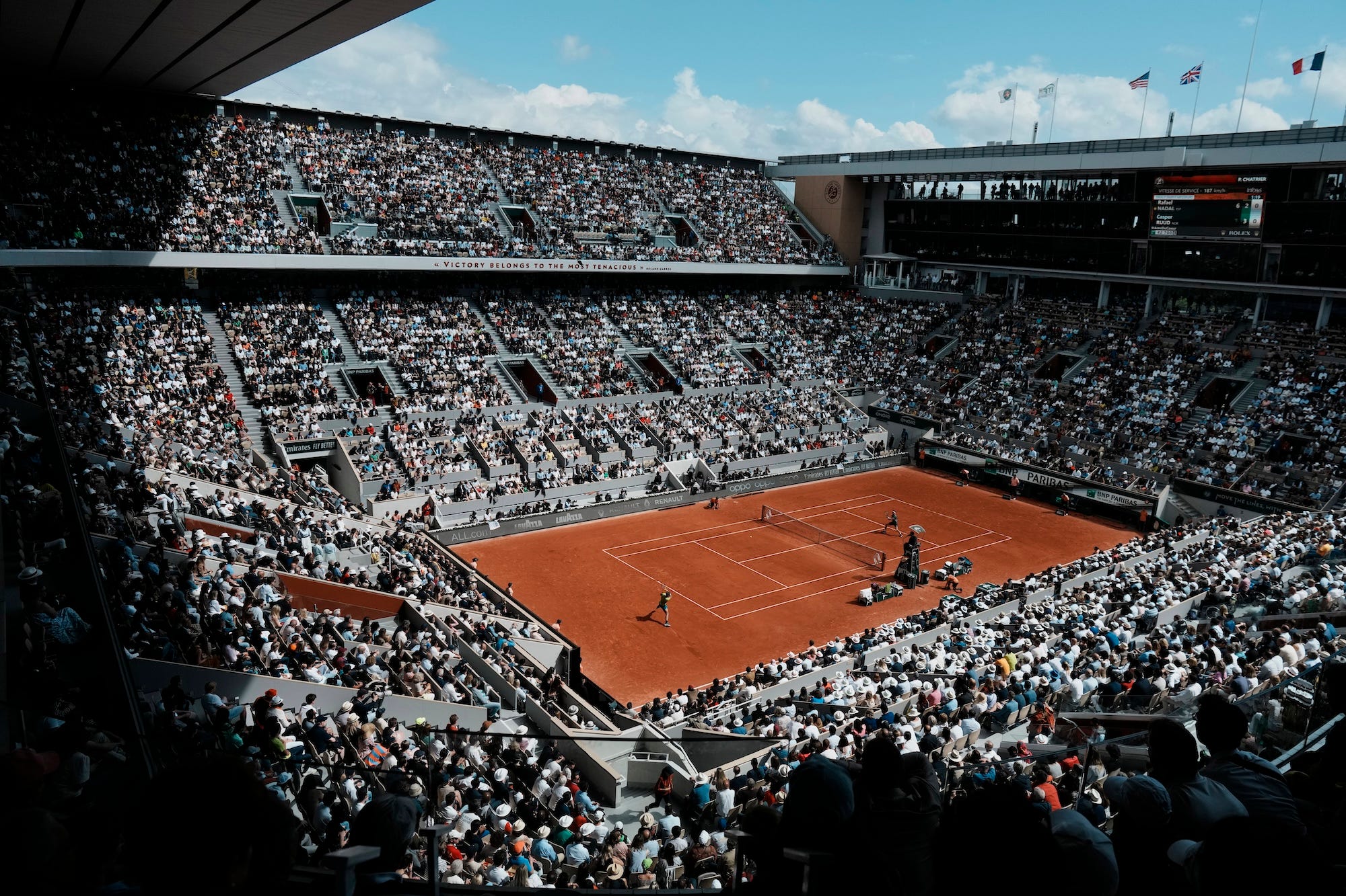 Crowds watch a tennis game at the French Open at Roland Garros stadium in Paris.