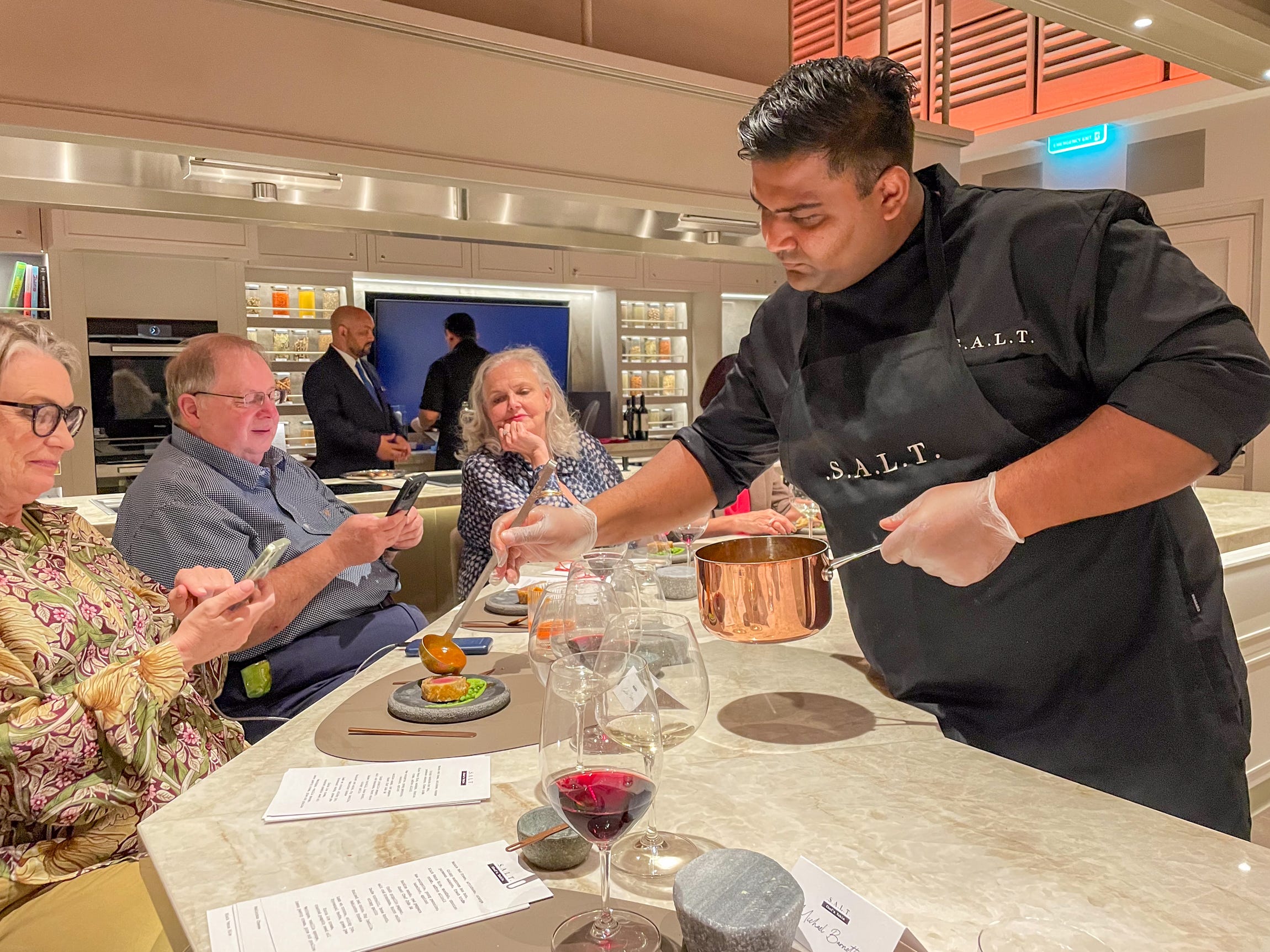 person pouring sauce over a guest's plate