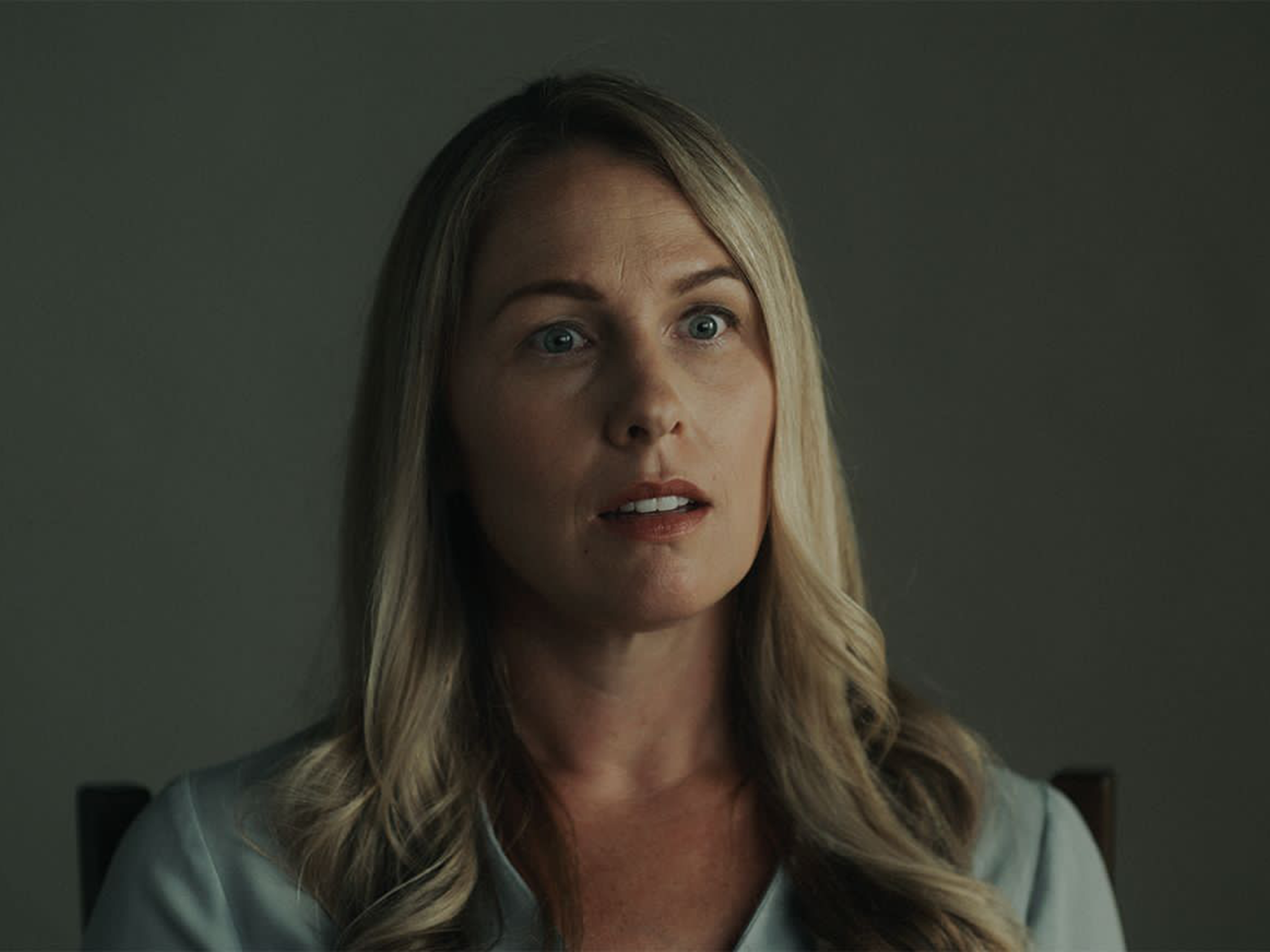 A still from "American Nightmare" showing a blonde woman sitting on a chair.