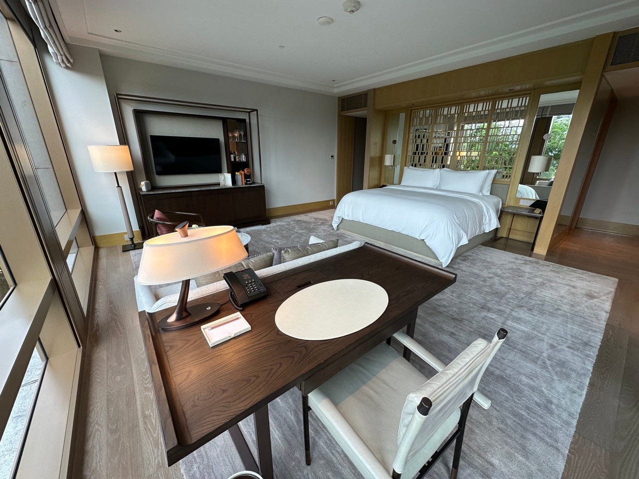 View of desk, chair, lamp and bed in hotel room 