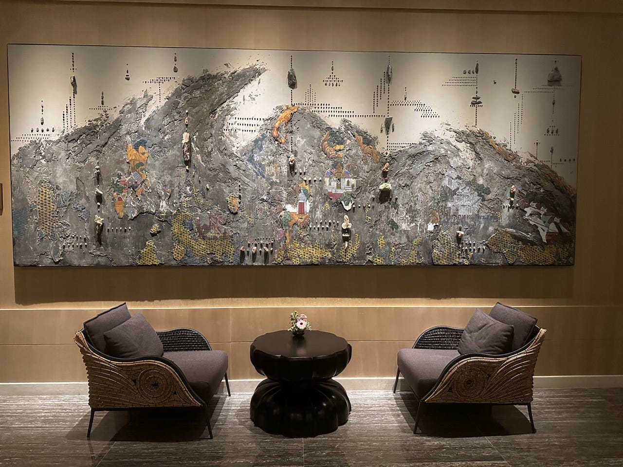 Textured artwork above two chairs and a table in lobby area