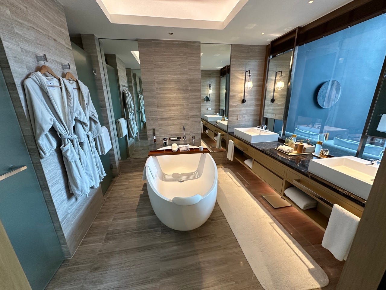 Large bathtub in center of bathroom with large vanity area with two big sinks 