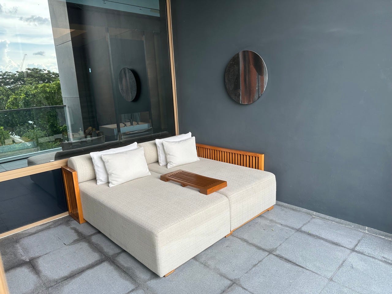 Large couch-like lounger with pillows on balcony next to mirror