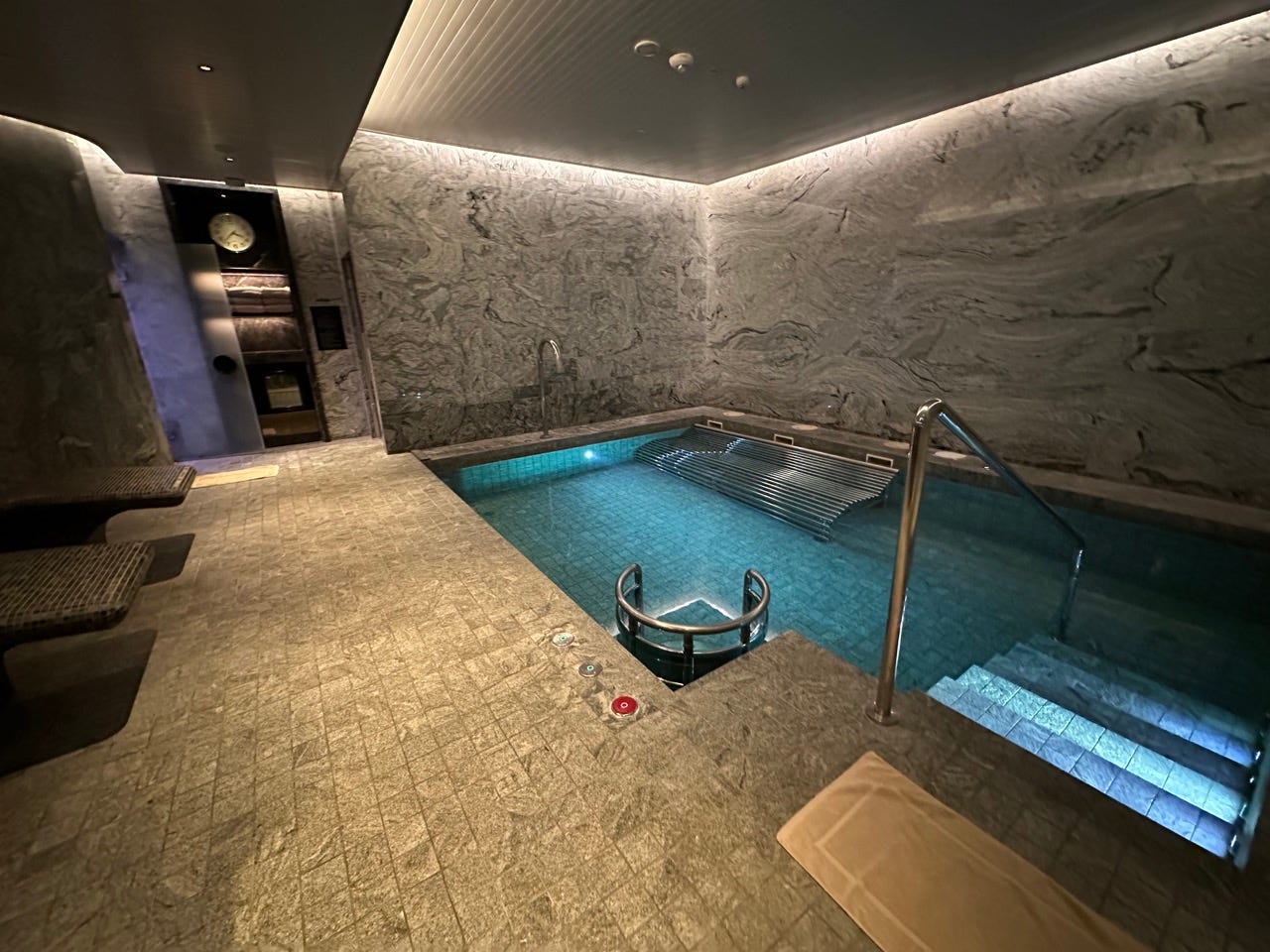 Indoor pool surrounded by stone and lighting 