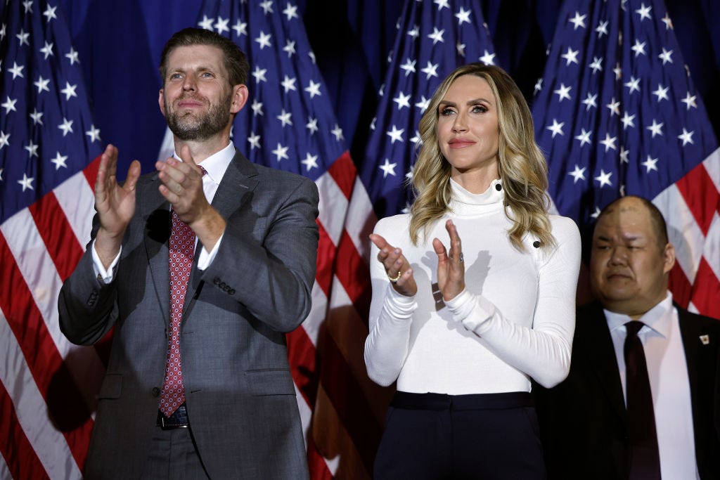 Eric Trump en Lara Trump staan voor grote Amerikaanse vlaggen. 