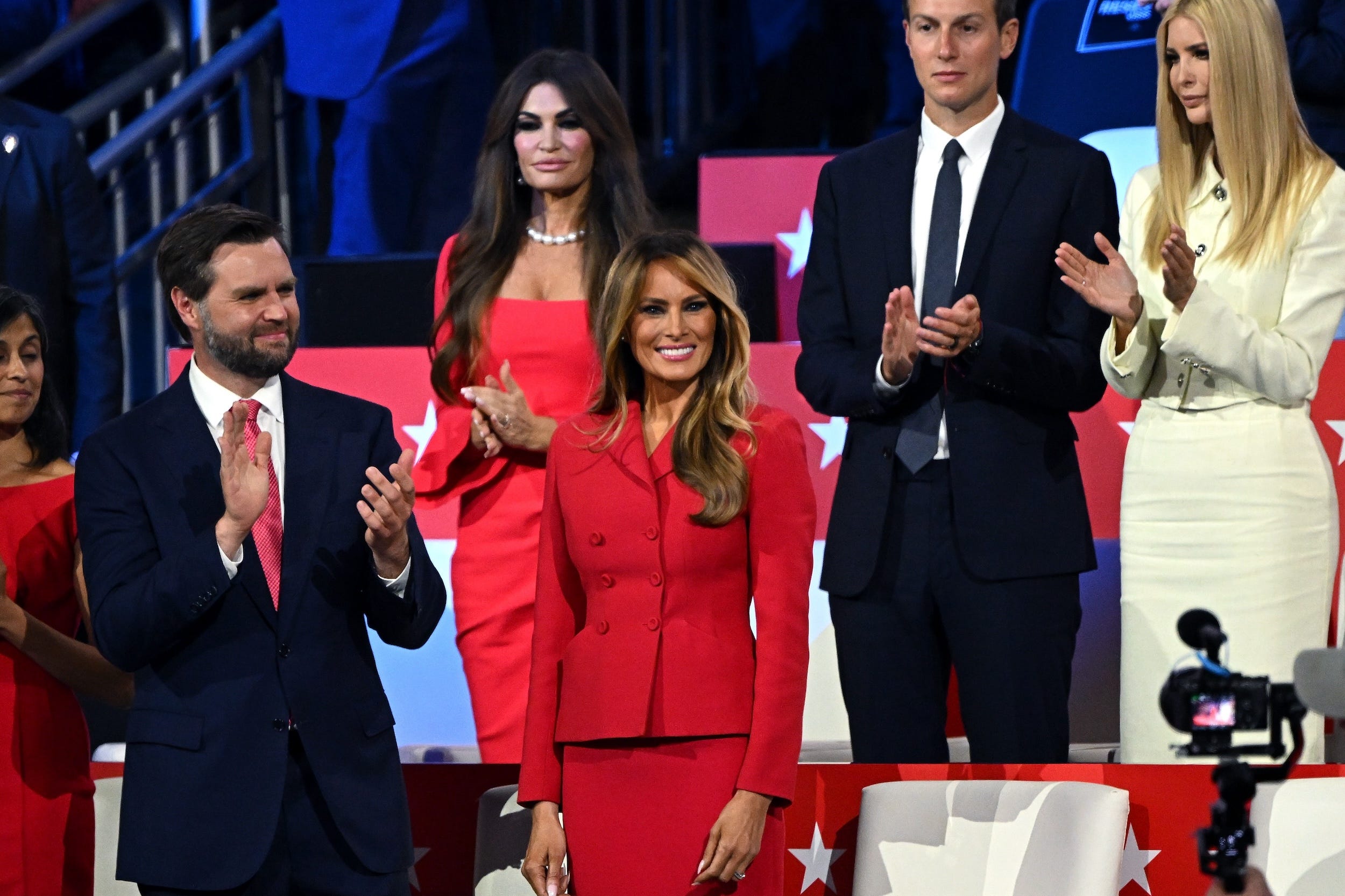 Sen. JD Vance staat naast Melania Trump in een rood pak. Achter haar staan Jared Kushner en Ivanka Trump in het wit.