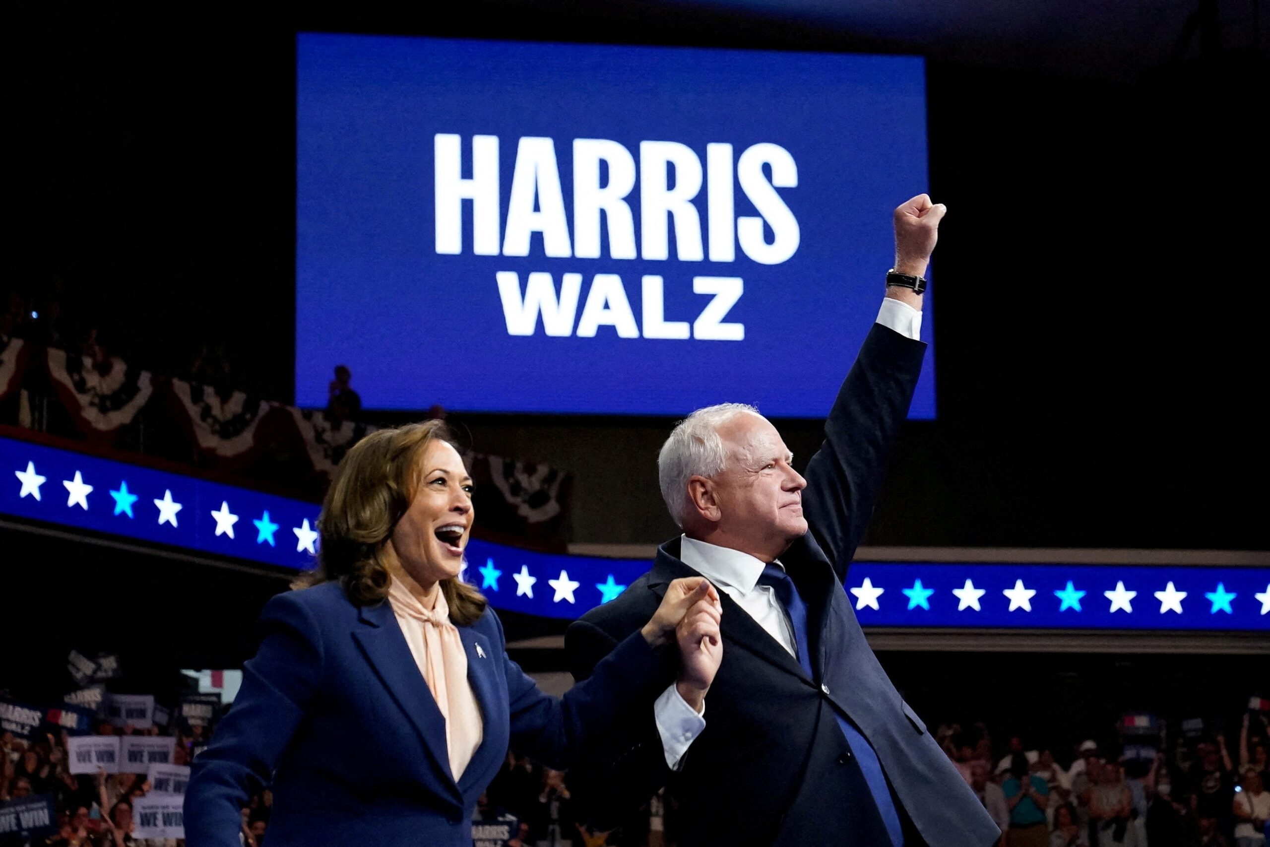 Kamala Harris and Tim Walz motion to the crowd during a Philadelphia campaign rally.