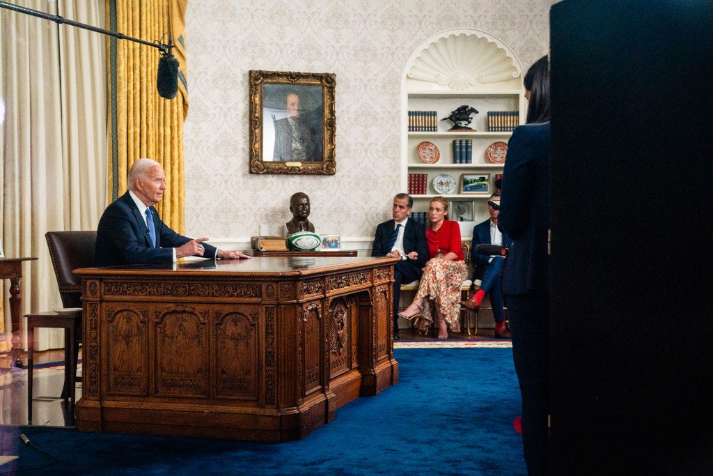 Joe Biden speaks in the Oval Office as his family members watch.