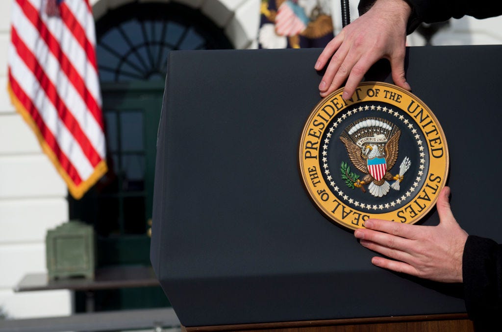 A presidential seal is placed on a podium in front of the White House.