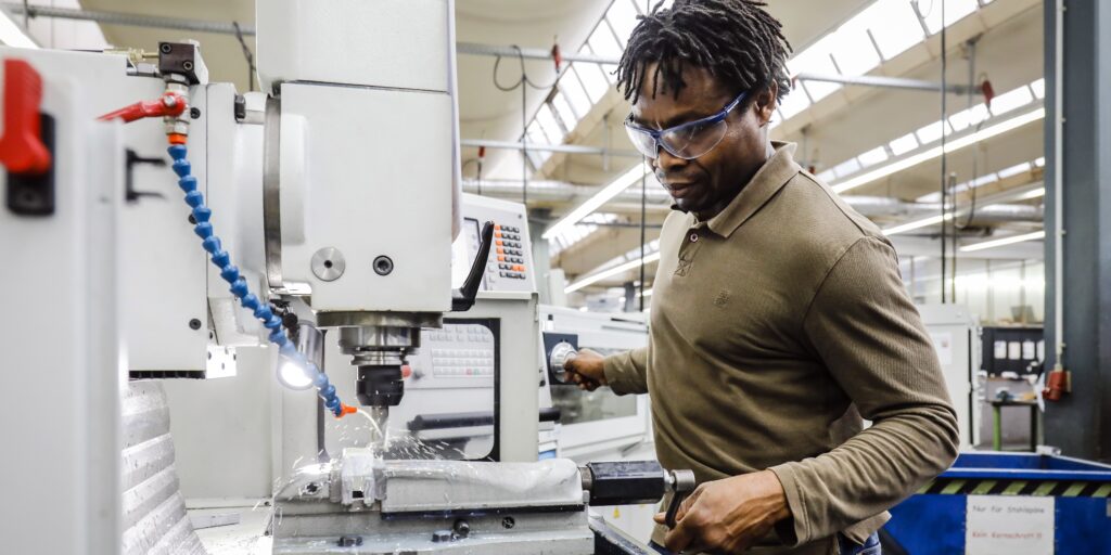 Een stagiair bewerkt metaal in een fabriek, in afwachting van zijn stagevergoeding.