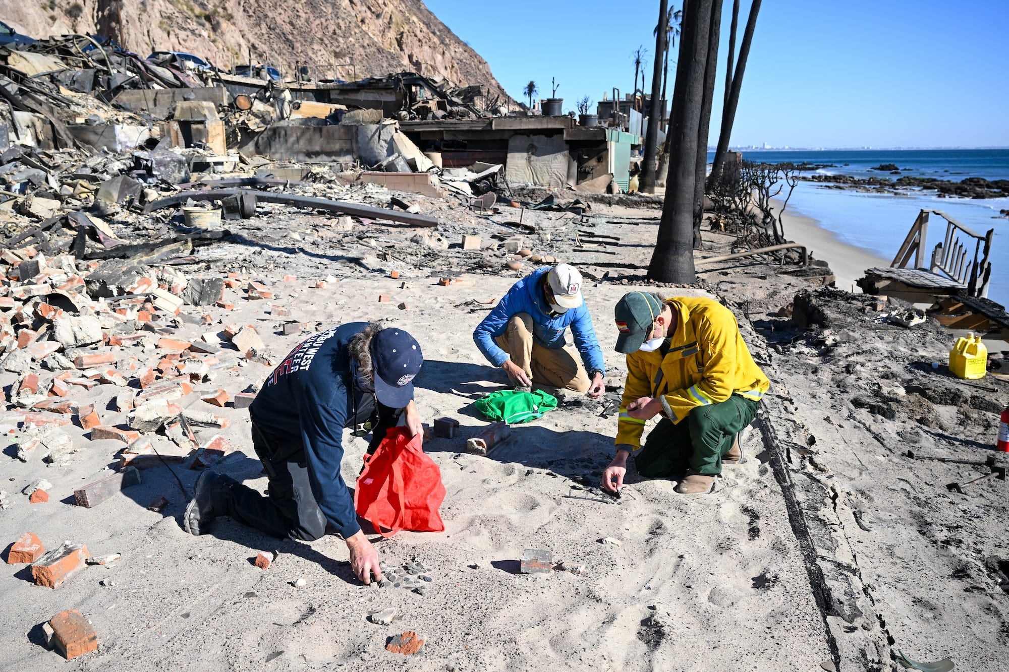 Residents look through for their valuables into ashes at their Malibu Beach burned home as Palisades wildfire continues in Los Angeles.