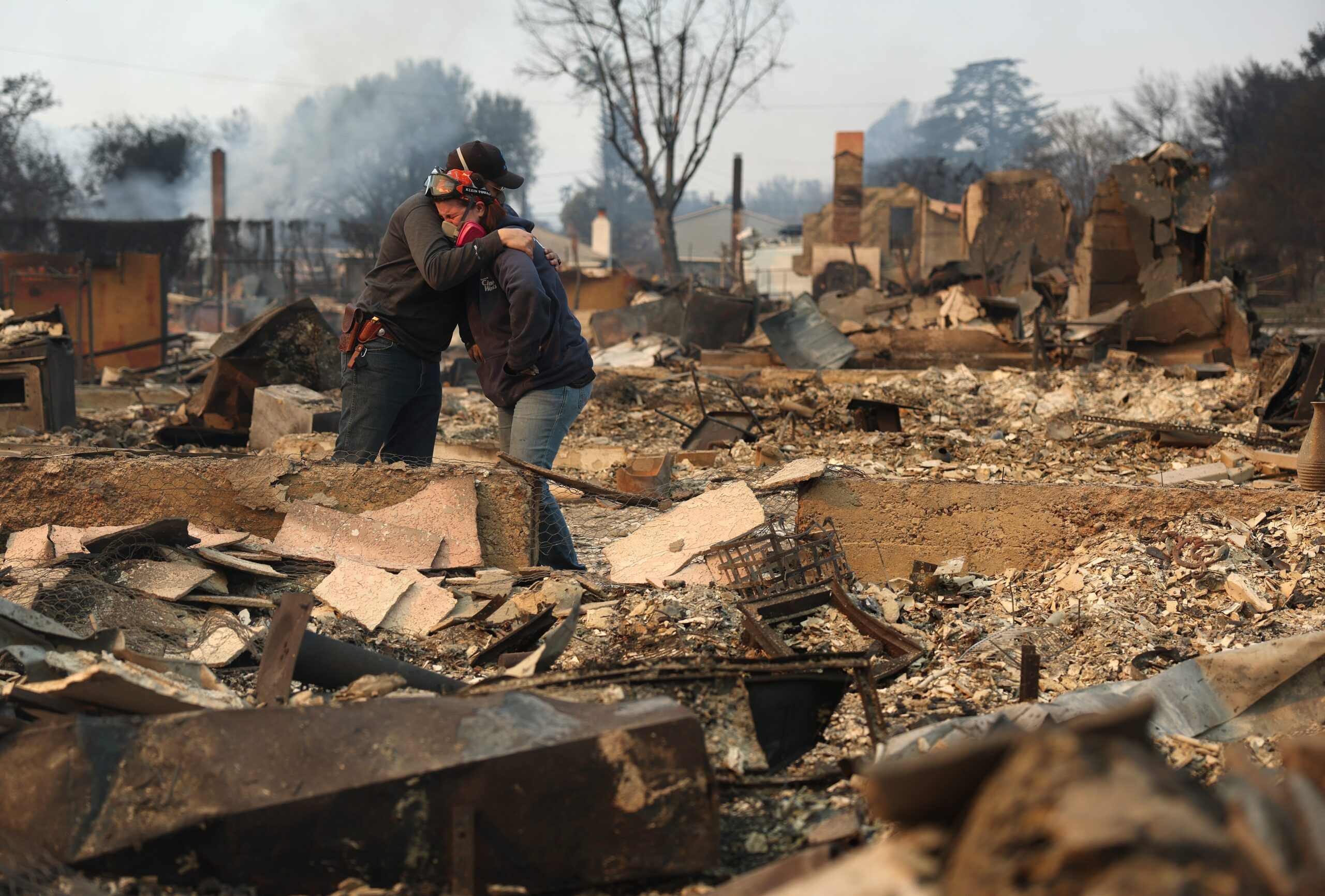 Khaled Fouad (L) and Mimi Laine (R) embrace as they inspect a family member's property that was destroyed by Eaton Fire on January 09, 2025 in Altadena, California. Fueled by intense Santa Ana Winds, the Eaton Fire has grown to over 10,000 acres and has destroyed many homes and businesses.