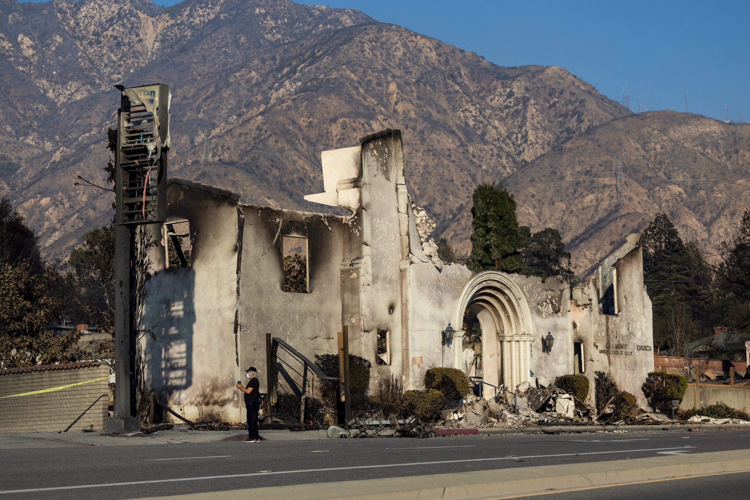 A person takes photos of scene of the Altadena Community Church that was burned in the Eaton fire in Altadena Saturday, Jan. 11, 2025