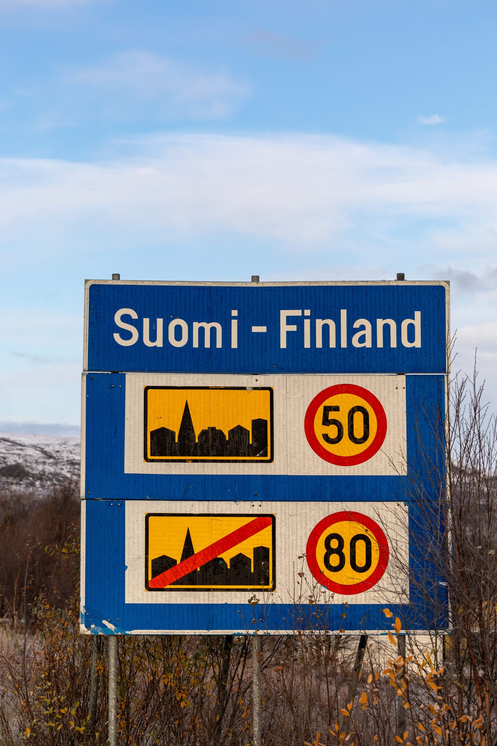 A blue road sign reading Suomi - Finland and speed limits of 50 and 80 in cities and non-cities