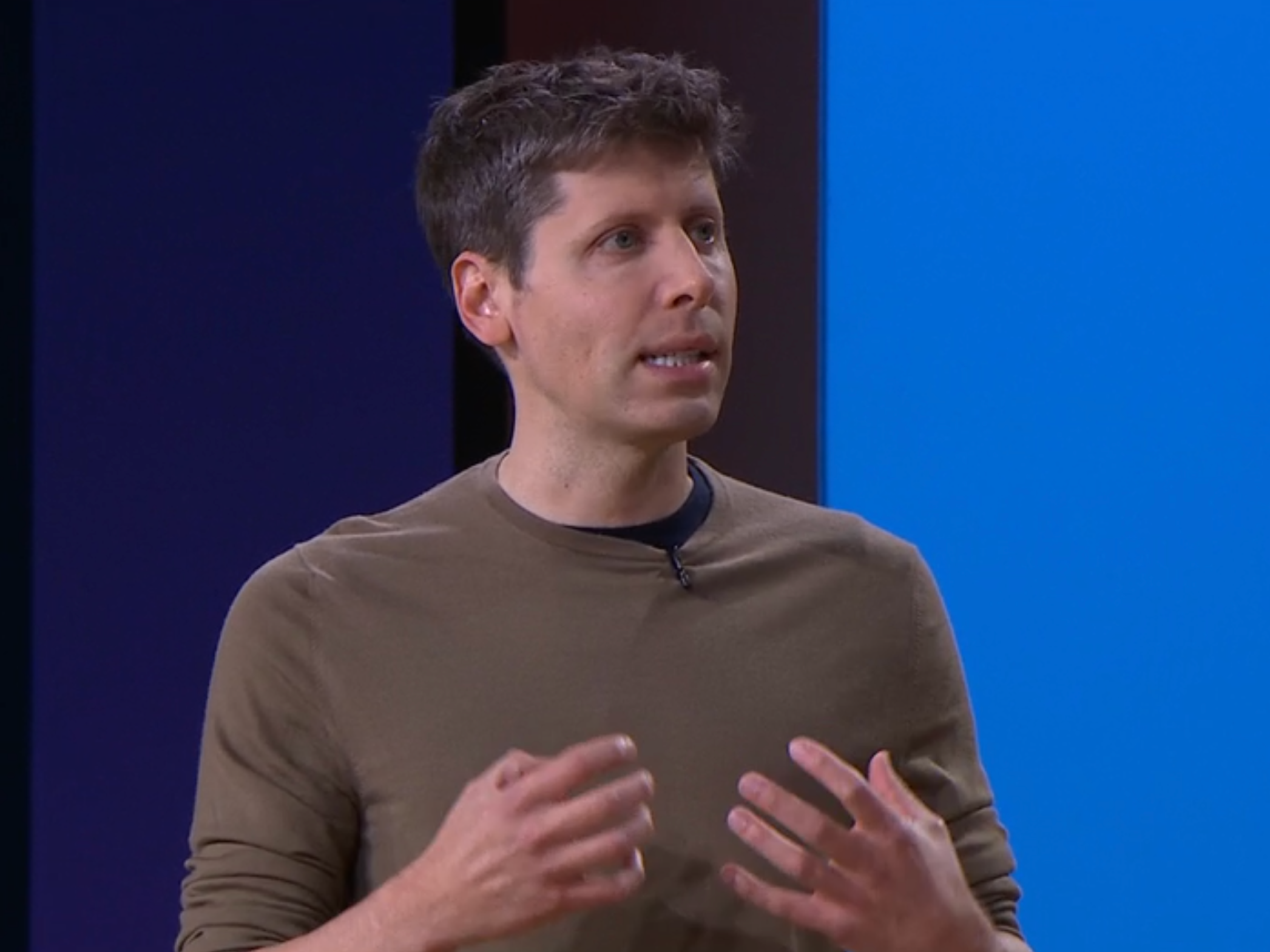 Sam Altman gestures while giving a speech at an event.