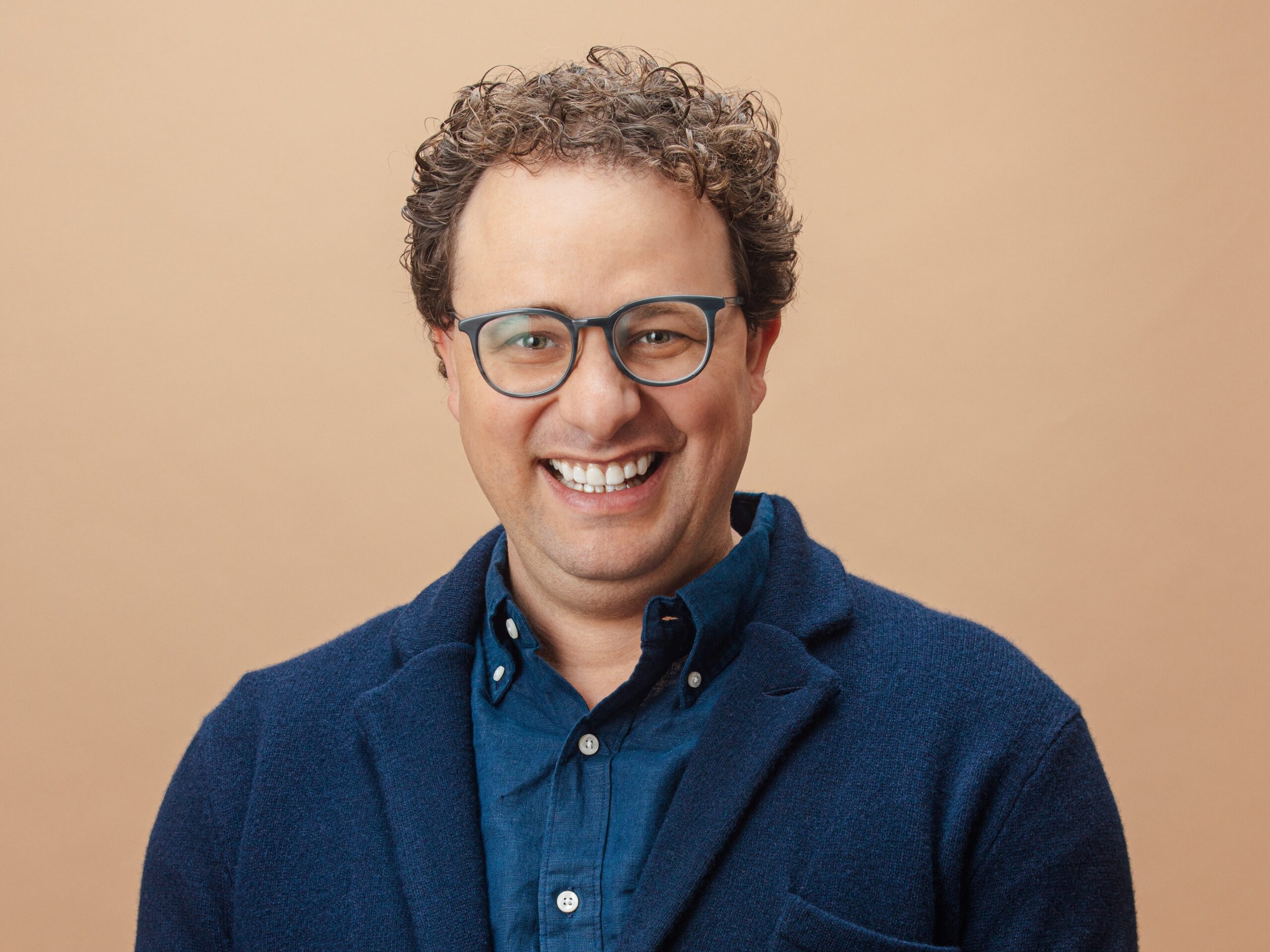 Dario Amodei, the CEO of Anthropic, sits in front of a tan background.