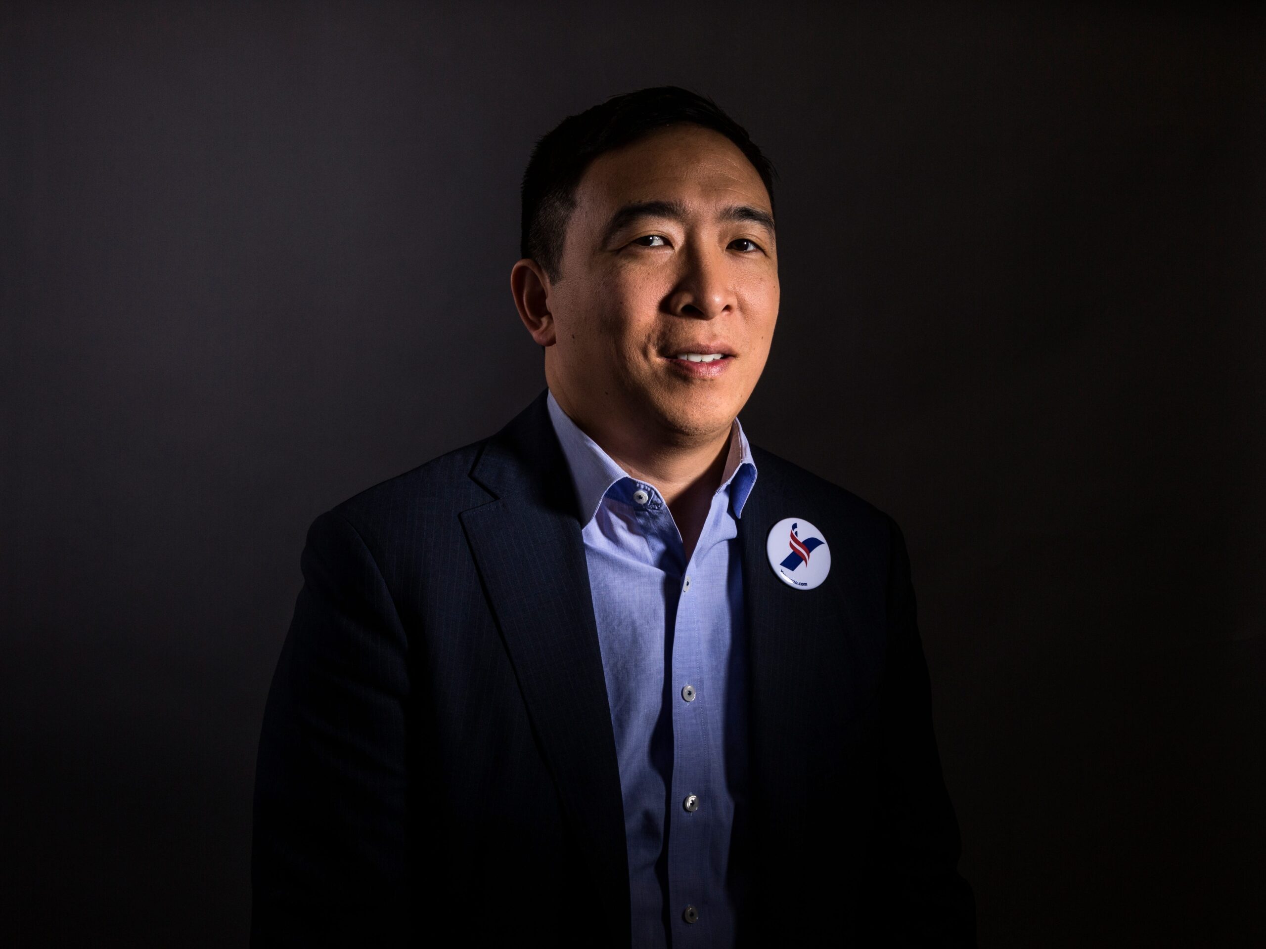 Andrew Yang poses for a photograph, wearing a pin from his presidential campaign.